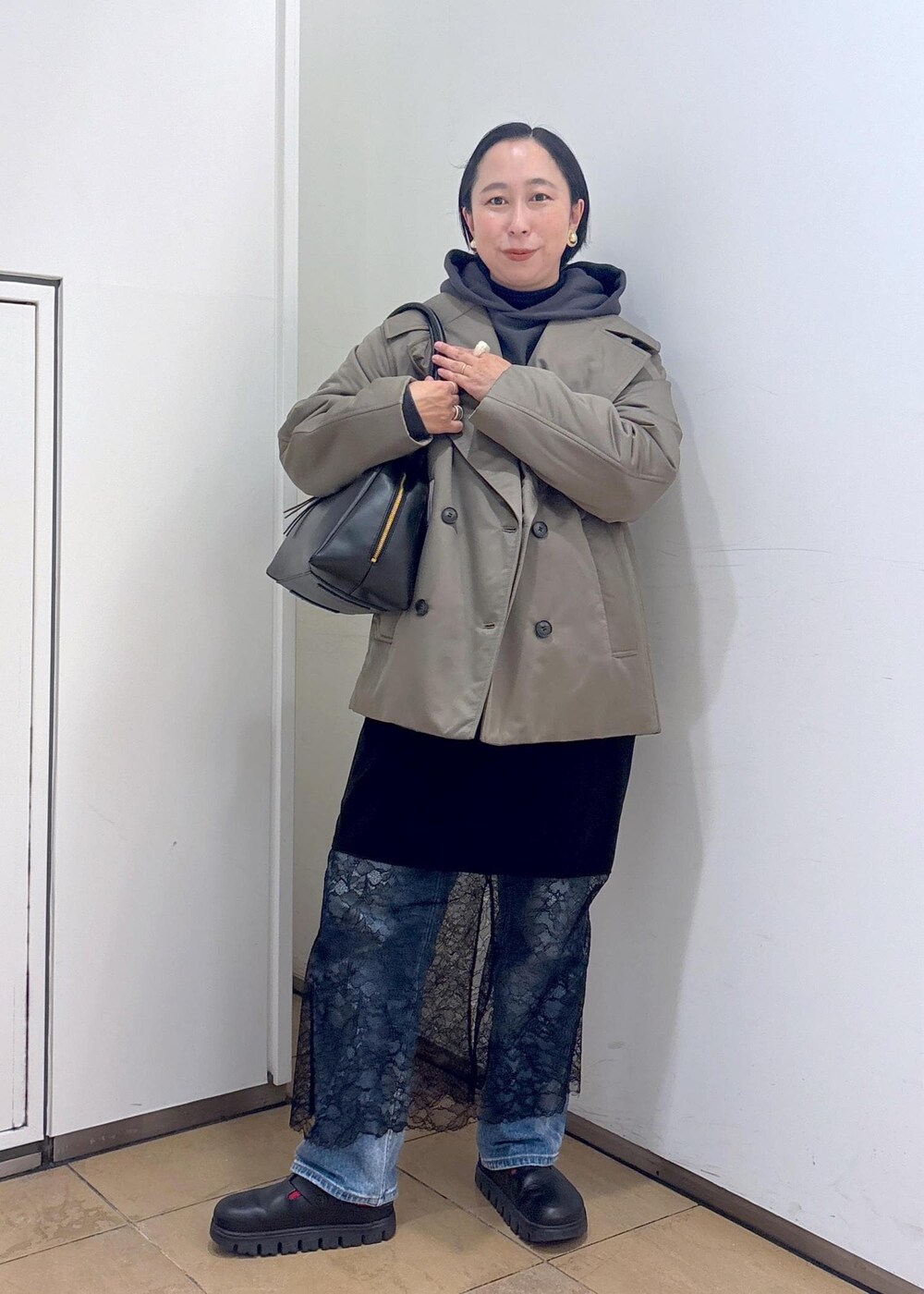 グレー系のパーカー、グリーン系のダウンジャケット/コート、ブラック系のボストンバッグを着用したレディースの冬コーディネートの3枚目の写真