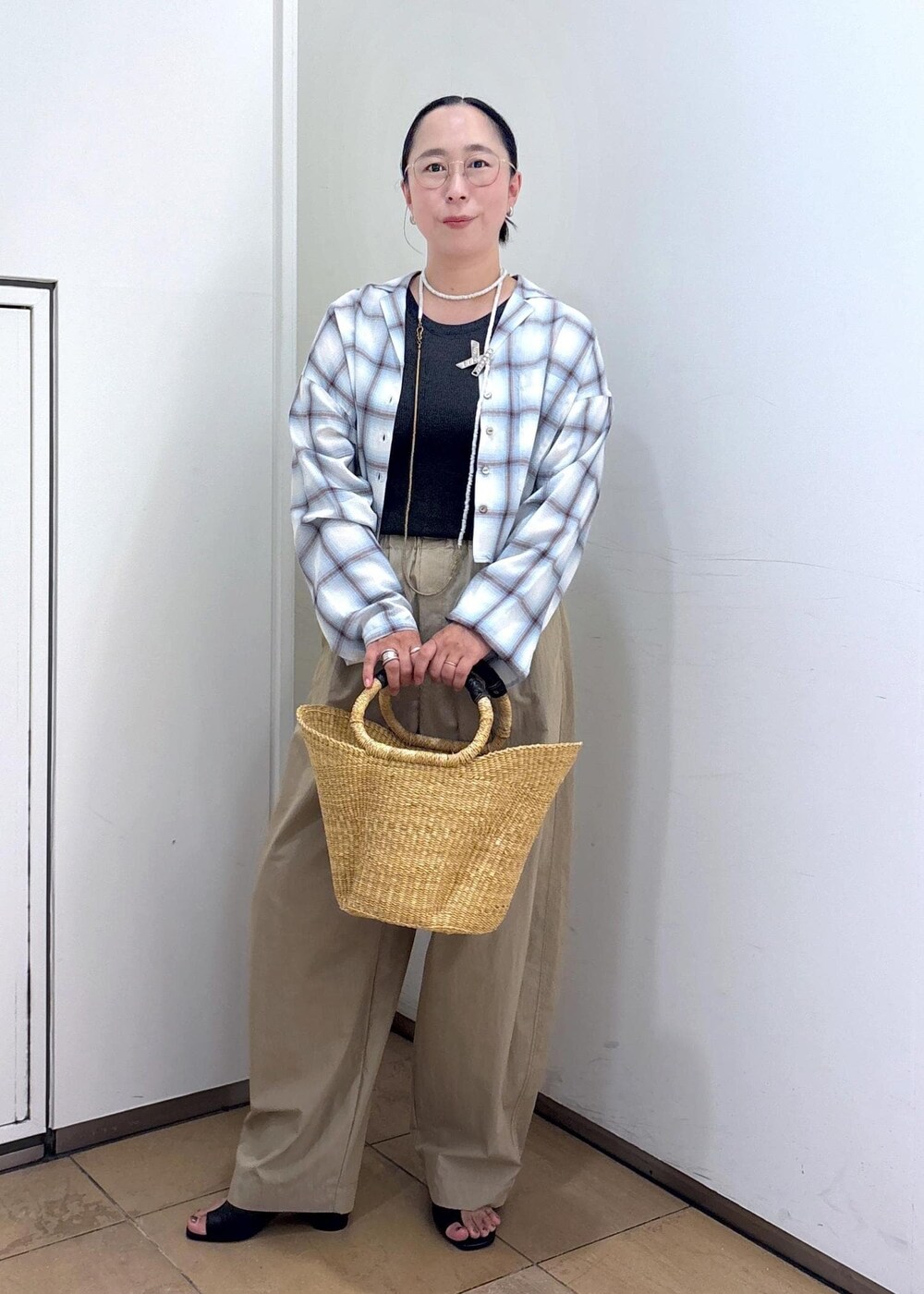 ホワイト系のトートバッグ、ブラック系のサンダル、グレー系のタンクトップを着用したレディースの夏コーディネートの3枚目の写真