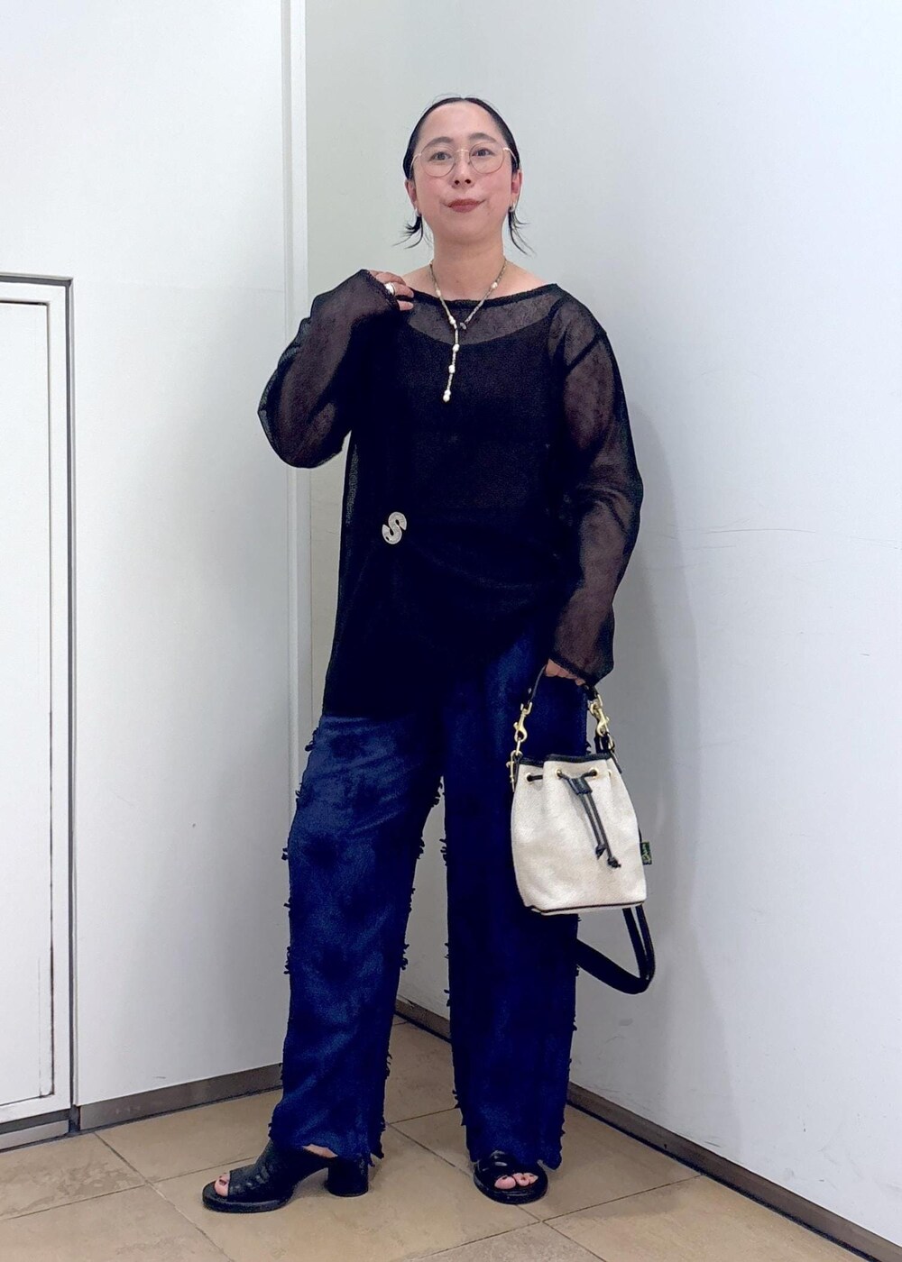 ブラック系のニット/セーター、ブルー系のその他パンツ、ホワイト系のショルダーバッグを着用したレディースの夏コーディネートの4枚目の写真