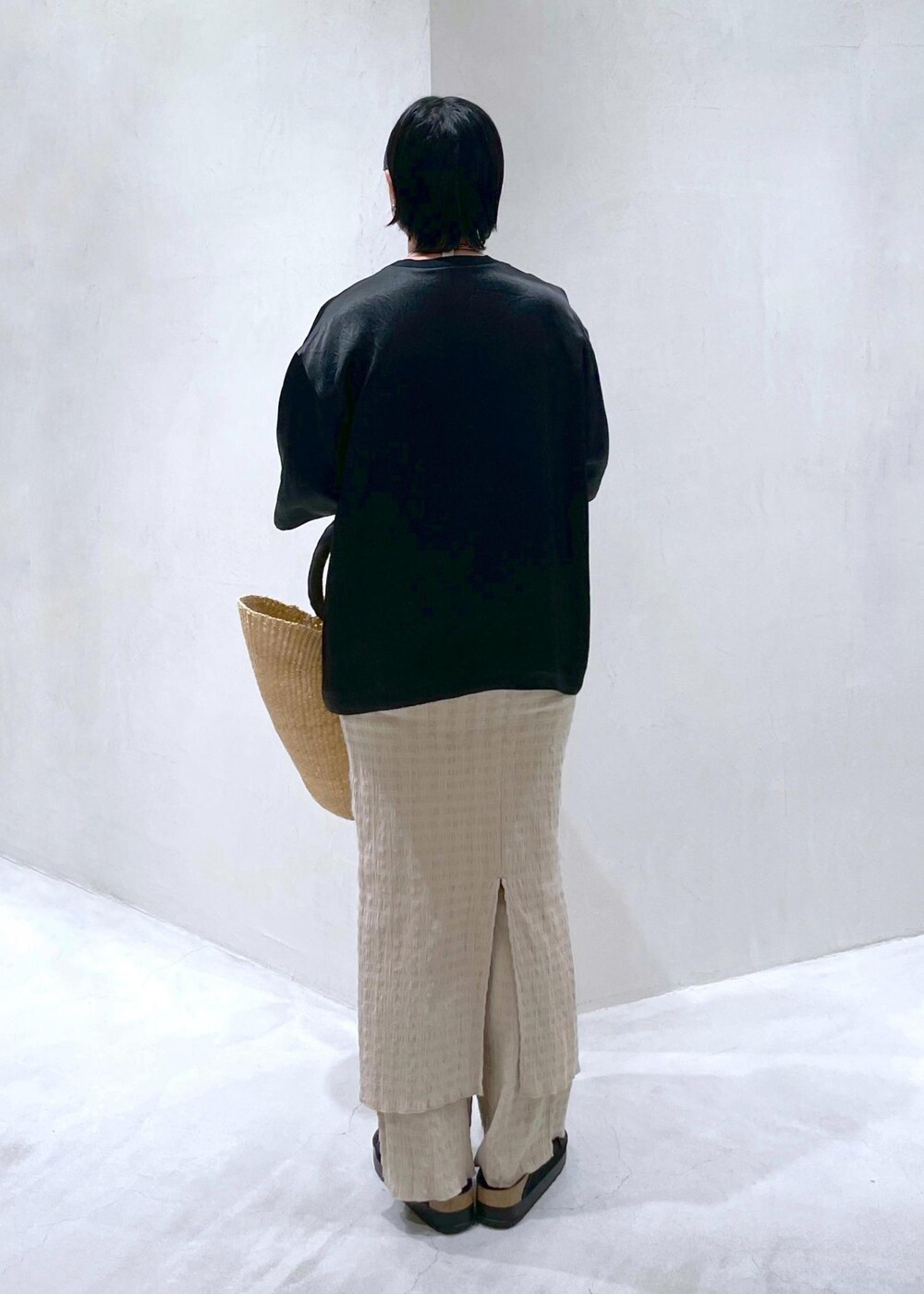 ブラック系のサンダル、ブラック系のTシャツ/カットソー、ベージュ系のかごバッグを着用したレディースの夏コーディネートの6枚目の写真