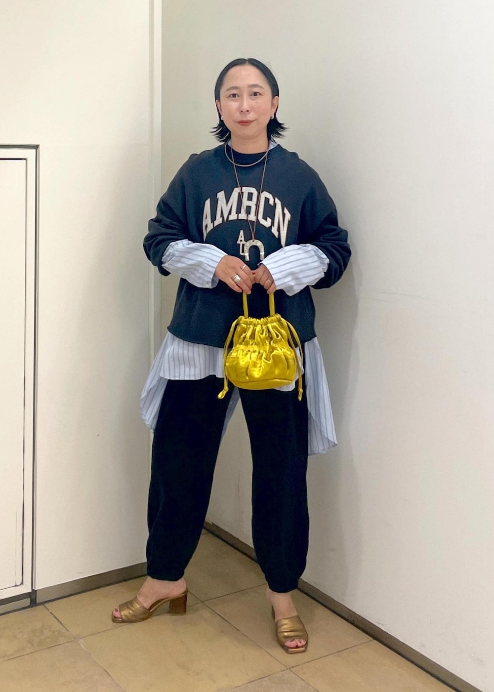 イエロー系のショルダーバッグ、ブラック系のスウェット、ブラック系のスウェットパンツを着用したレディースの夏コーディネートの4枚目の写真