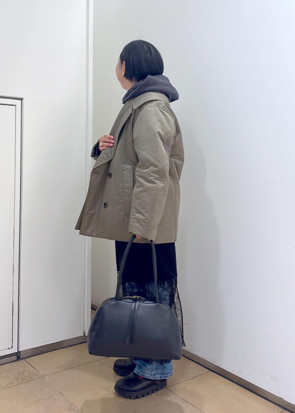 グレー系のパーカー、グリーン系のダウンジャケット/コート、ブラック系のボストンバッグを着用したレディースの冬コーディネートの6枚目の写真