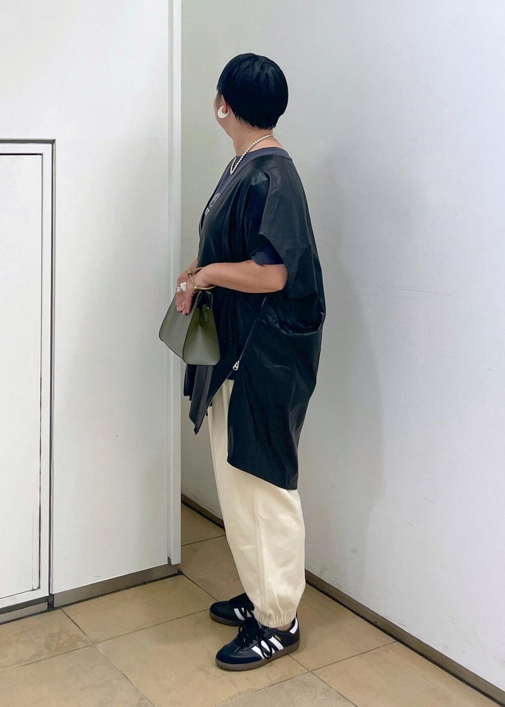 グリーン系のショルダーバッグ、ブラック系のTシャツ/カットソー、ホワイト系のスウェットパンツを着用したレディースの夏コーディネートの6枚目の写真