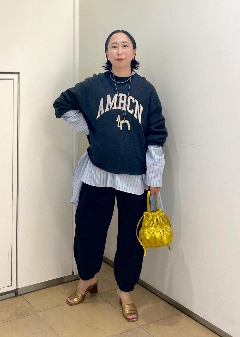 イエロー系のショルダーバッグ、ブラック系のスウェット、ブラック系のスウェットパンツを着用したレディースの夏コーディネートの2枚目の写真