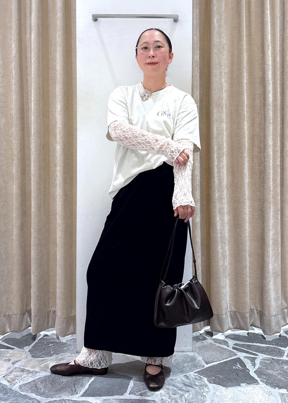 ブラック系のスカート、ホワイト系のその他トップス、ブラウン系のハンドバッグを着用したレディースの夏コーディネートの3枚目の写真