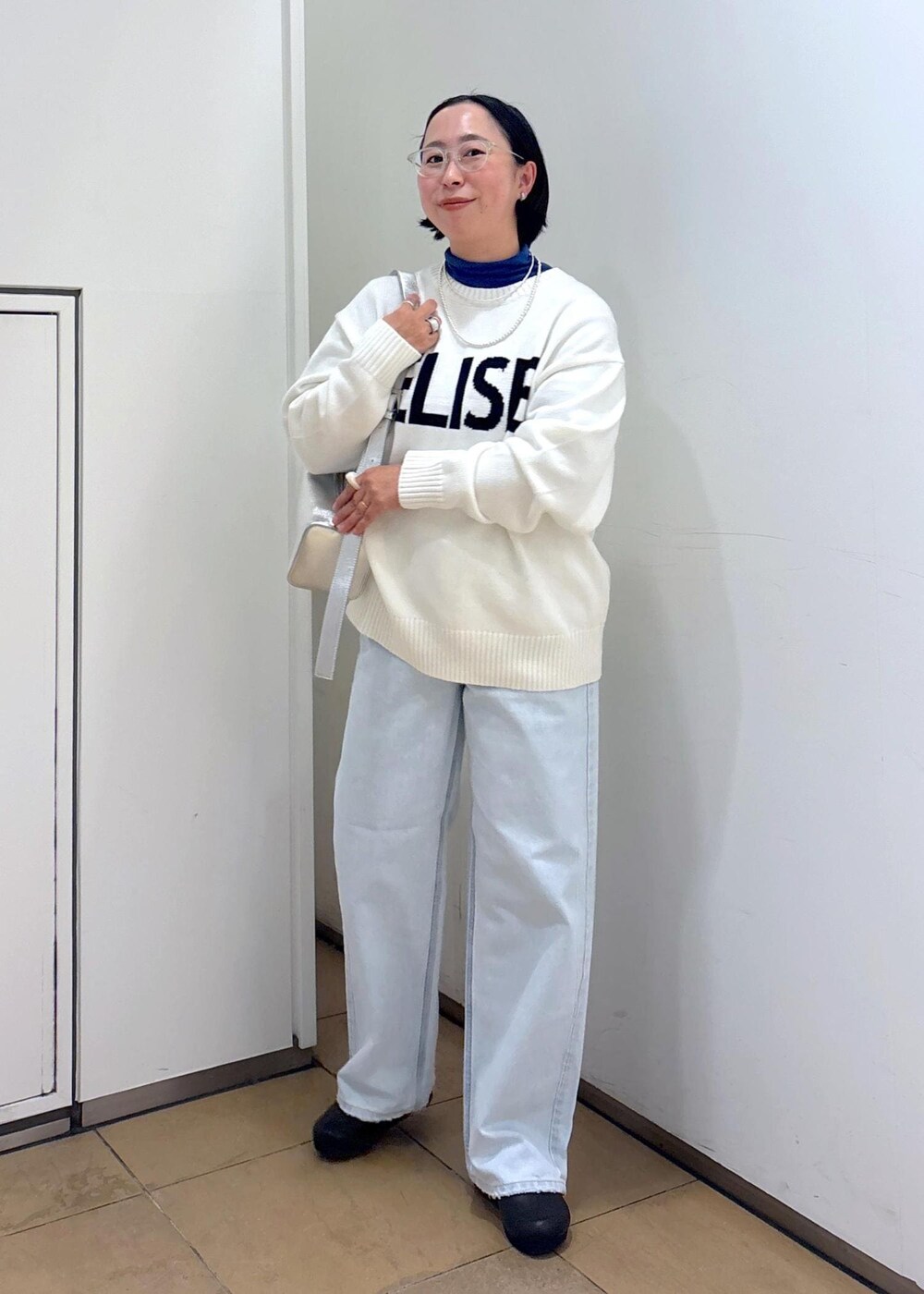 ホワイト系のニット/セーター、シルバー系のショルダーバッグ、ブルー系のデニムパンツを着用したレディースの冬コーディネートの4枚目の写真