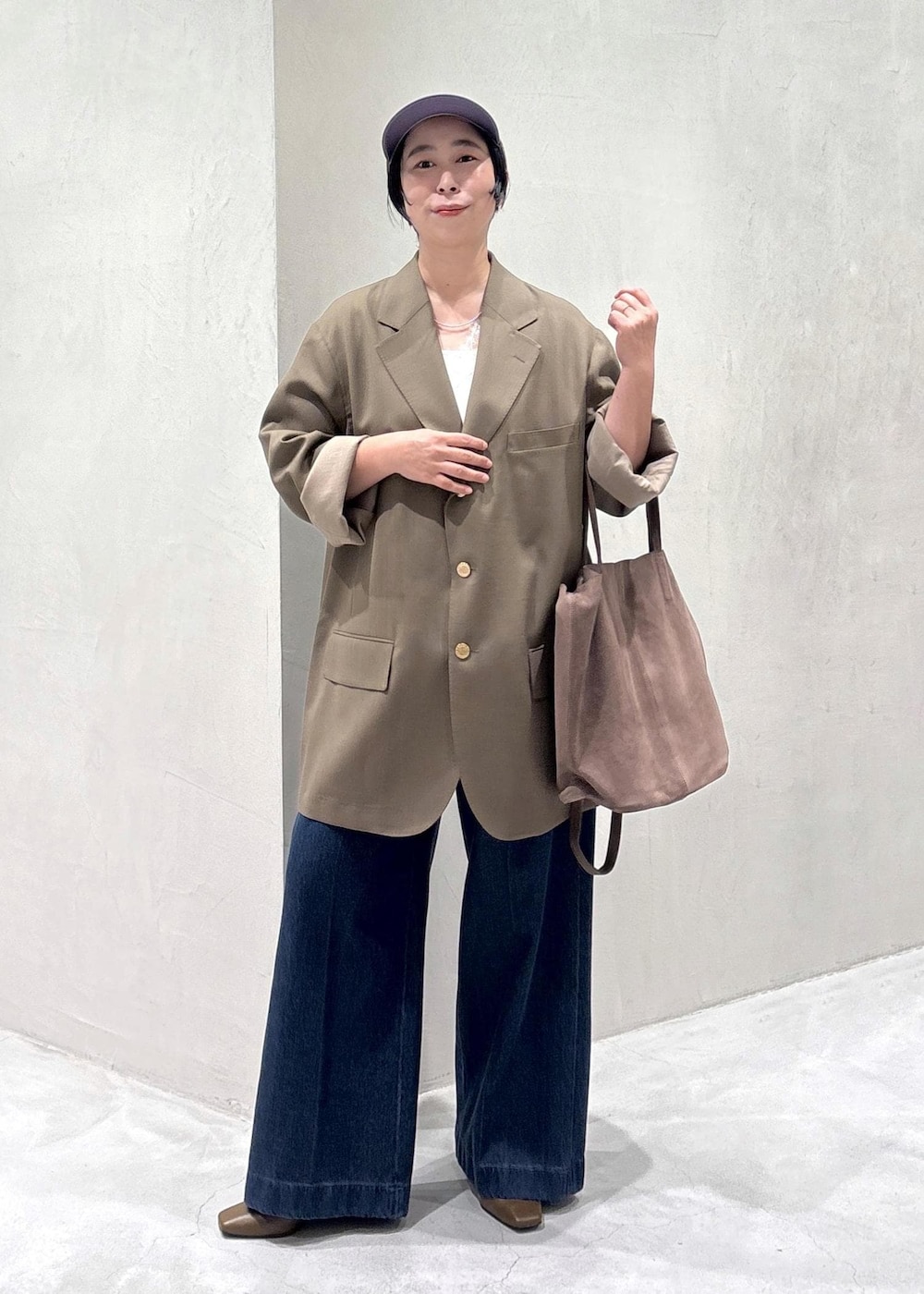 ブラウン系のパンプス、ホワイト系のキャミソール、ブルー系のデニムパンツを着用したレディースの冬コーディネートの3枚目の写真