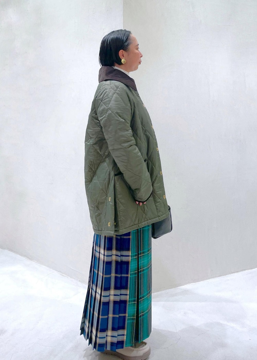 ブラック系のハンドバッグ、グリーン系のスカート、ホワイト系のTシャツ/カットソーを着用したレディースの秋コーディネートの2枚目の写真