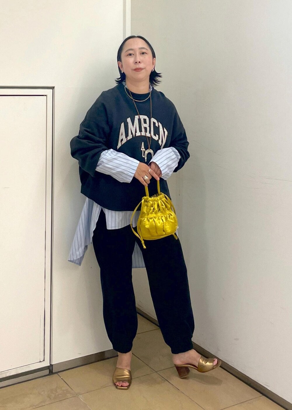 イエロー系のショルダーバッグ、ブラック系のスウェット、ブラック系のスウェットパンツを着用したレディースの夏コーディネートの5枚目の写真