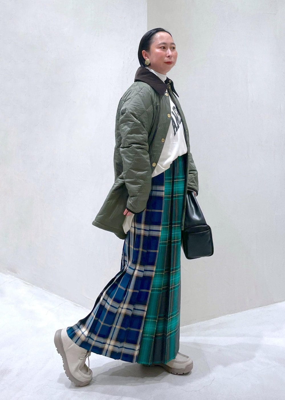 ブラック系のハンドバッグ、グリーン系のスカート、ホワイト系のTシャツ/カットソーを着用したレディースの秋コーディネートの5枚目の写真