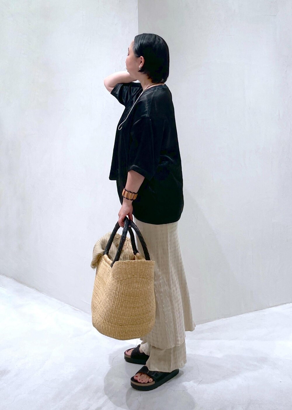 ブラック系のサンダル、ブラック系のTシャツ/カットソー、ベージュ系のかごバッグを着用したレディースの夏コーディネートの5枚目の写真