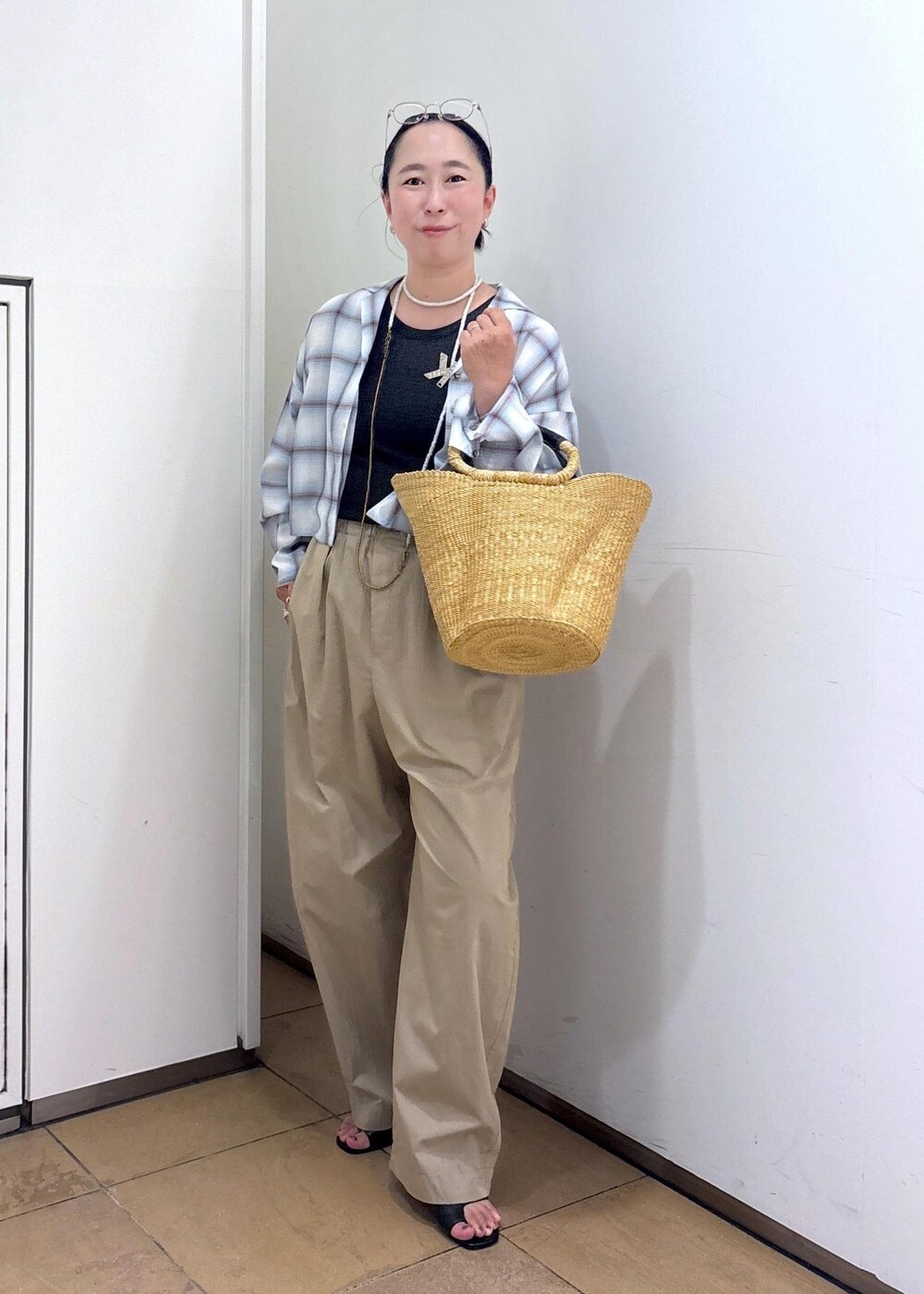 ホワイト系のトートバッグ、ブラック系のサンダル、グレー系のタンクトップを着用したレディースの夏コーディネートの2枚目の写真