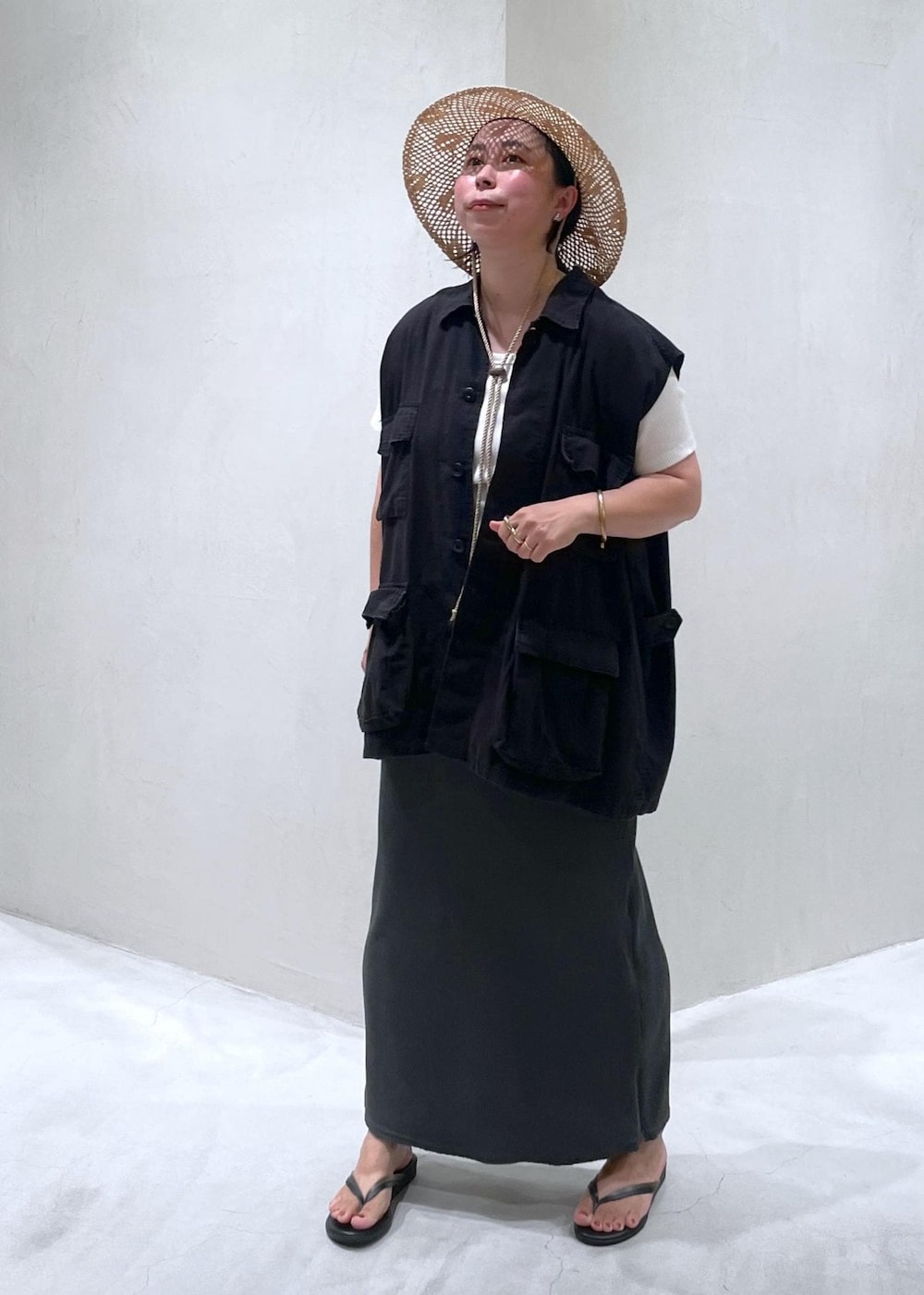 ブラック系のサンダル、ブラック系のベスト、ホワイト系のTシャツ/カットソーを着用したレディースの夏コーディネートの3枚目の写真