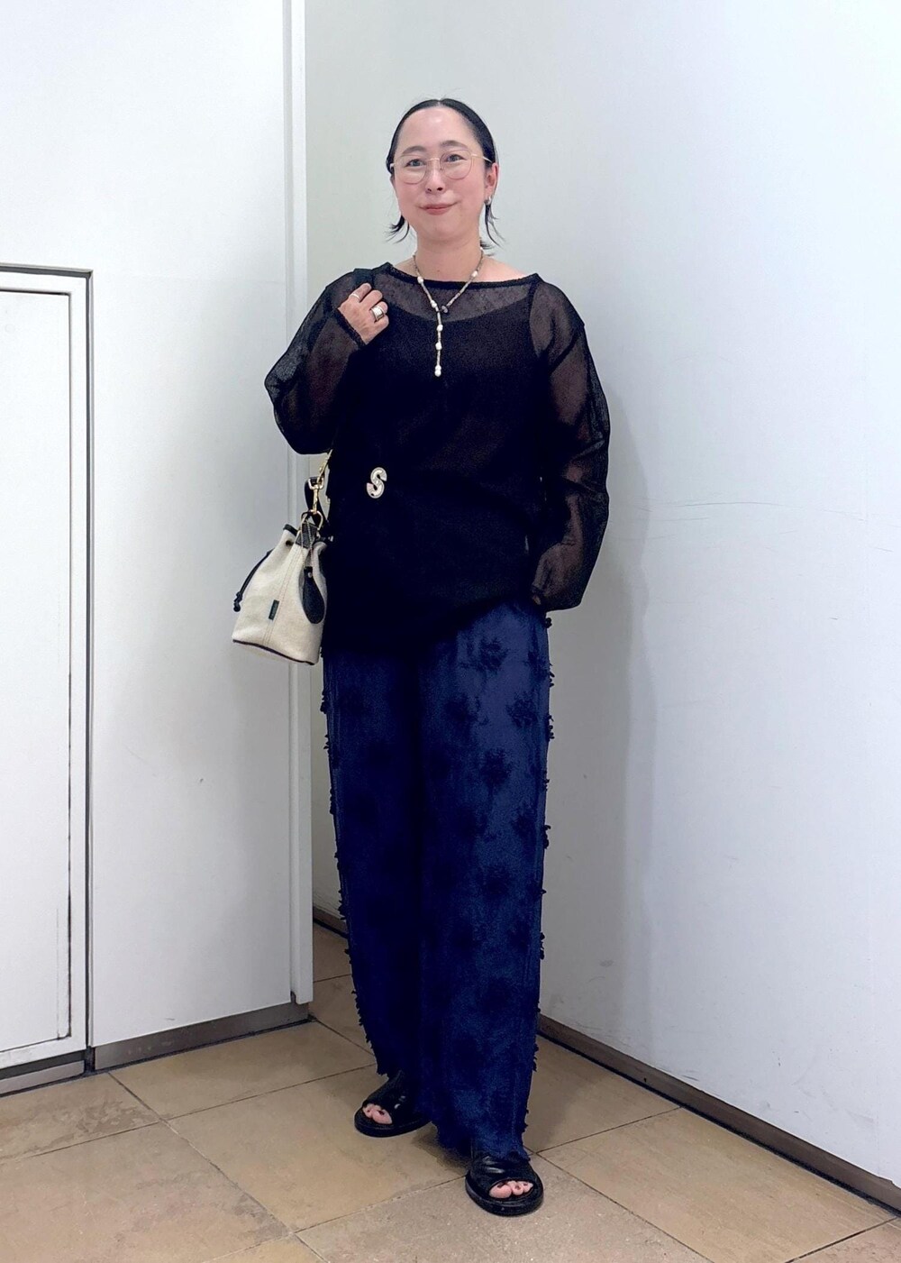 ブラック系のニット/セーター、ブルー系のその他パンツ、ホワイト系のショルダーバッグを着用したレディースの夏コーディネートの2枚目の写真