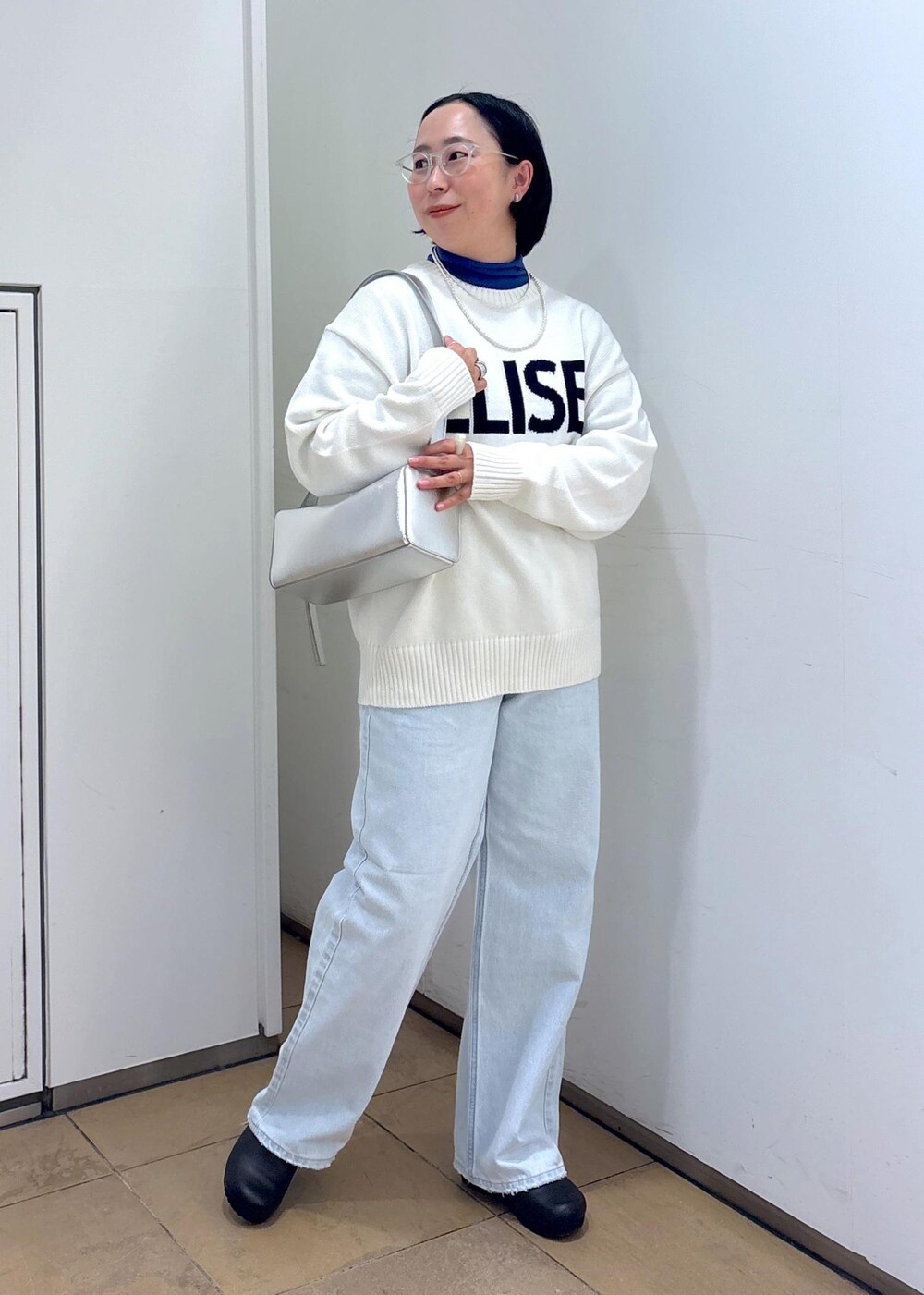 ホワイト系のニット/セーター、シルバー系のショルダーバッグ、ブルー系のデニムパンツを着用したレディースの冬コーディネートの2枚目の写真