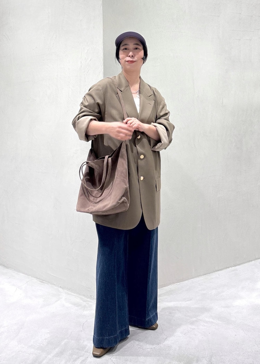 ブラウン系のパンプス、ホワイト系のキャミソール、ブルー系のデニムパンツを着用したレディースの冬コーディネートの2枚目の写真