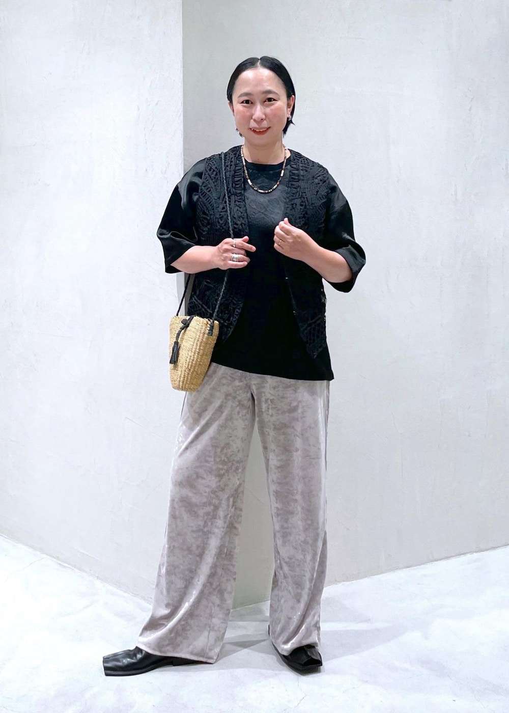 ベージュ系のかごバッグ、ブラック系のベスト、ベージュ系のその他パンツを着用したレディースの夏コーディネートの2枚目の写真