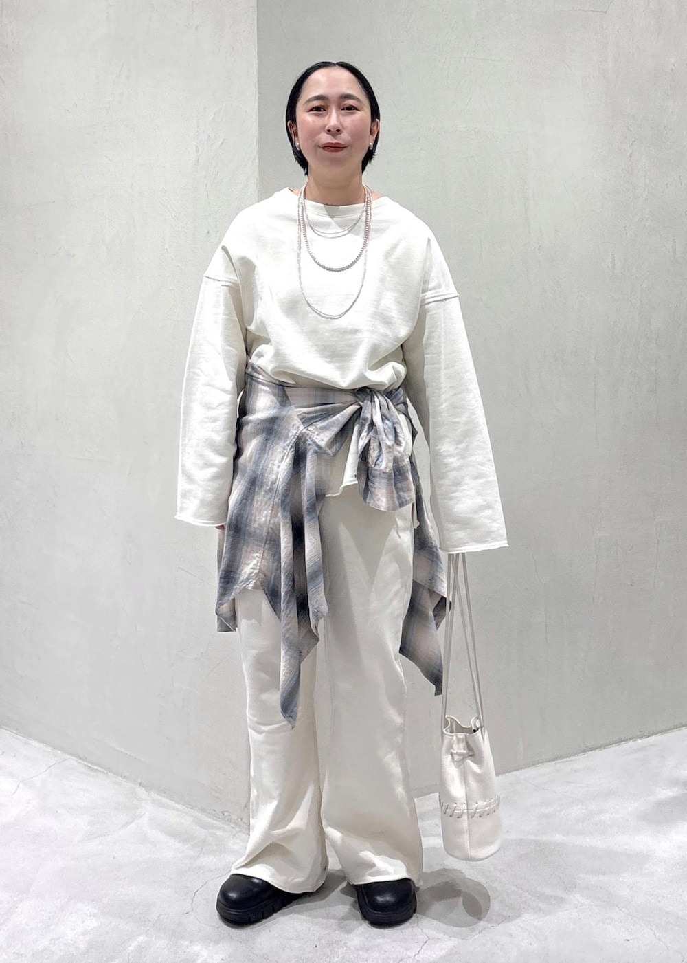 ブラック系のスニーカー、ホワイト系のショルダーバッグ、ブルー系のシャツ/ブラウスを着用したレディースの春コーディネートの2枚目の写真