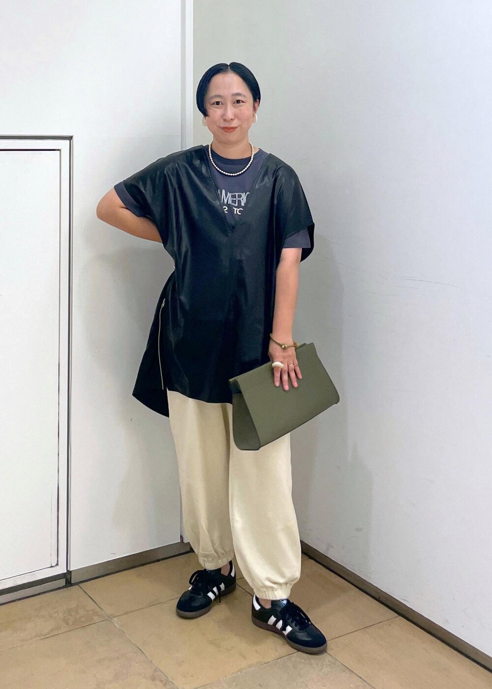 グリーン系のショルダーバッグ、ブラック系のTシャツ/カットソー、ホワイト系のスウェットパンツを着用したレディースの夏コーディネートの2枚目の写真