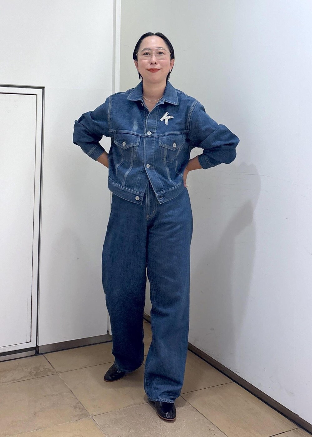 ブルー系のデニムジャケット、ブルー系のデニムパンツ、ブラック系のパンプスを着用したレディースの秋コーディネートの4枚目の写真