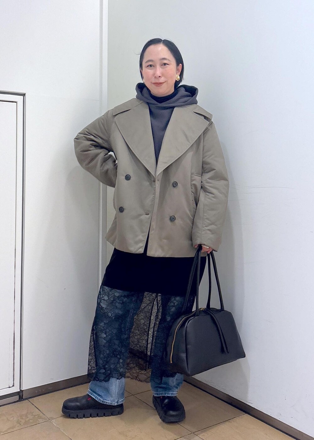 グレー系のパーカー、グリーン系のダウンジャケット/コート、ブラック系のボストンバッグを着用したレディースの冬コーディネートの2枚目の写真