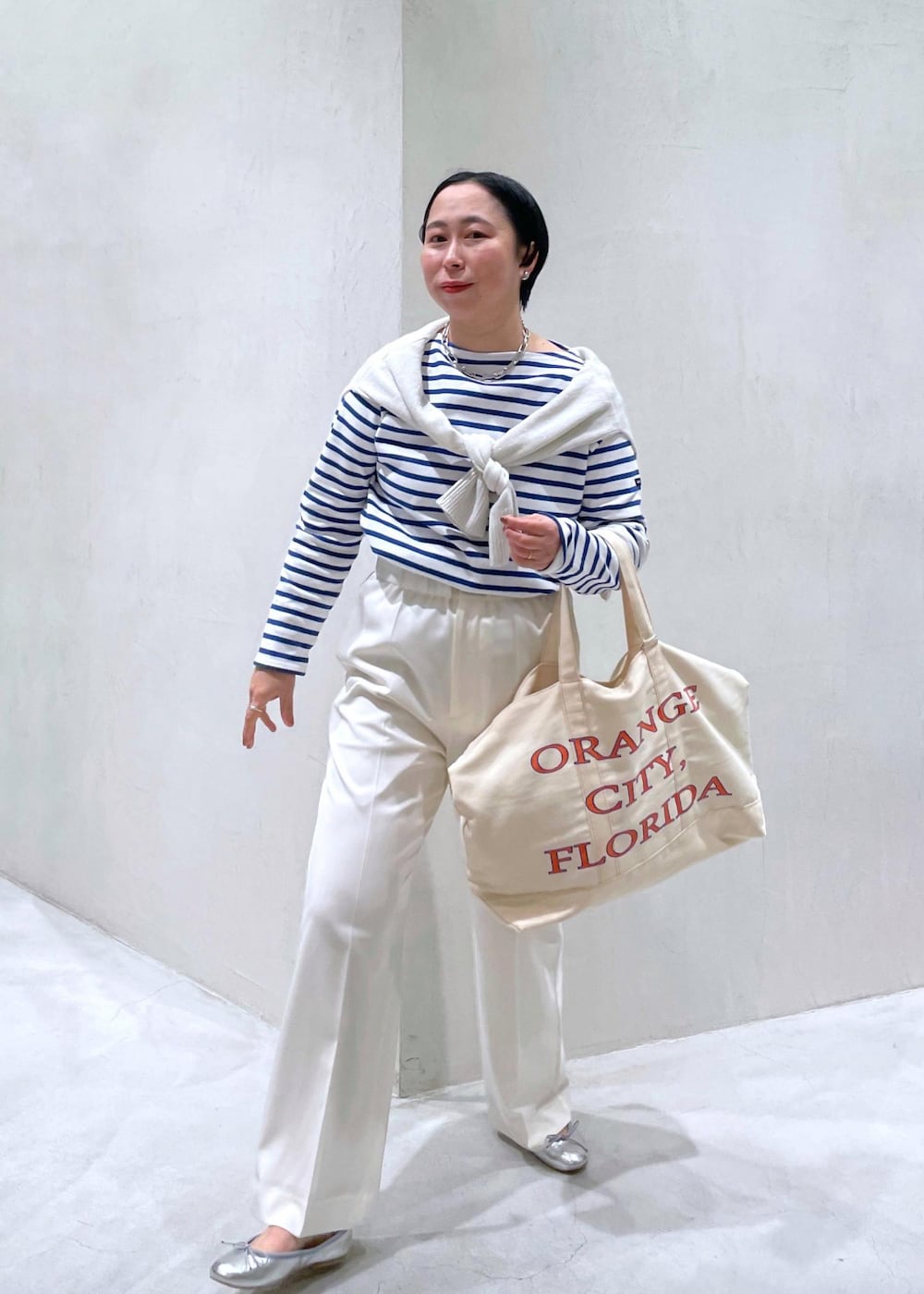 ブルー系のTシャツ/カットソー、シルバー系のバレエシューズ、ホワイト系のニット/セーターを着用したレディースの冬コーディネートの2枚目の写真