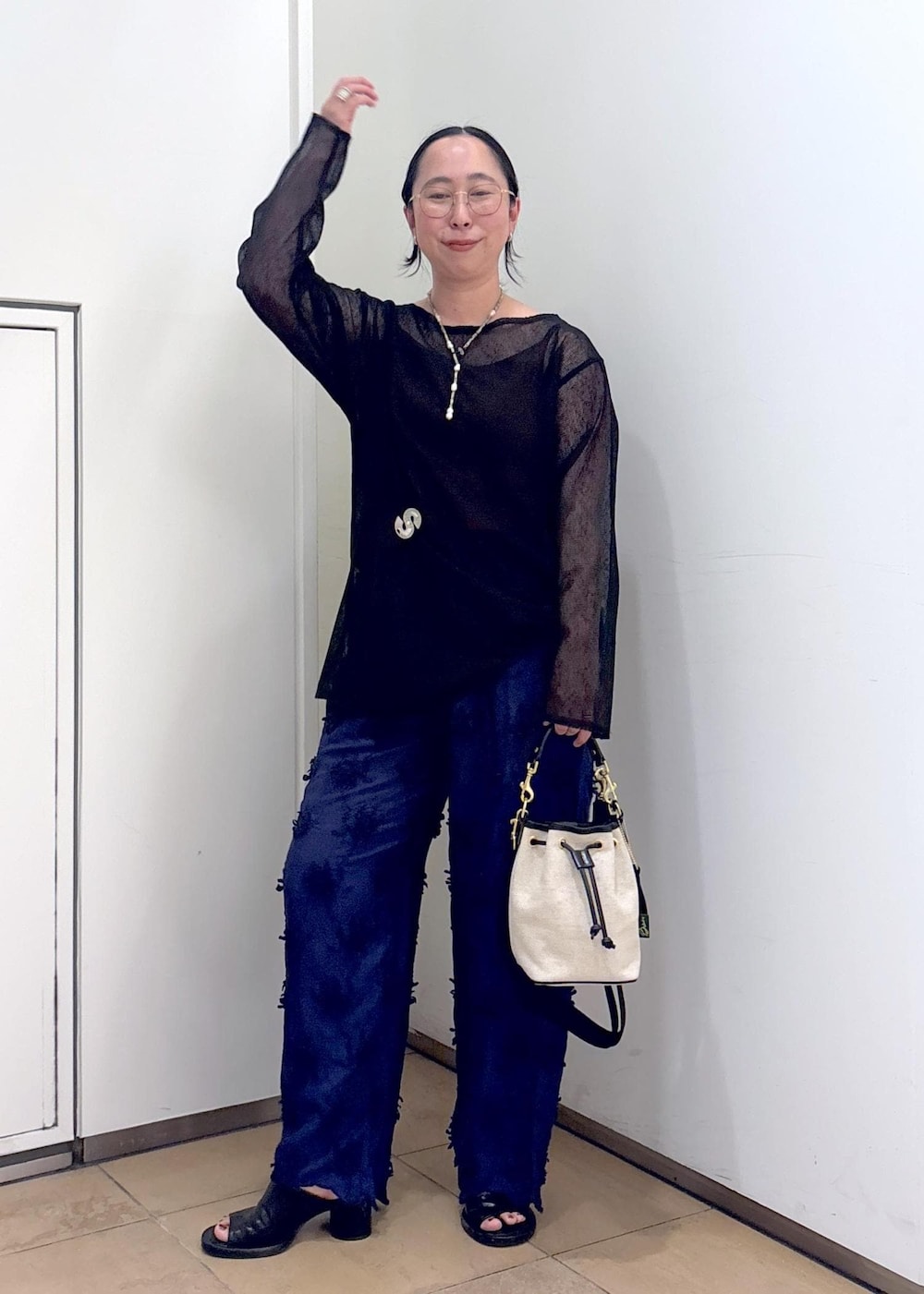 ブラック系のニット/セーター、ブルー系のその他パンツ、ホワイト系のショルダーバッグを着用したレディースの夏コーディネートの6枚目の写真