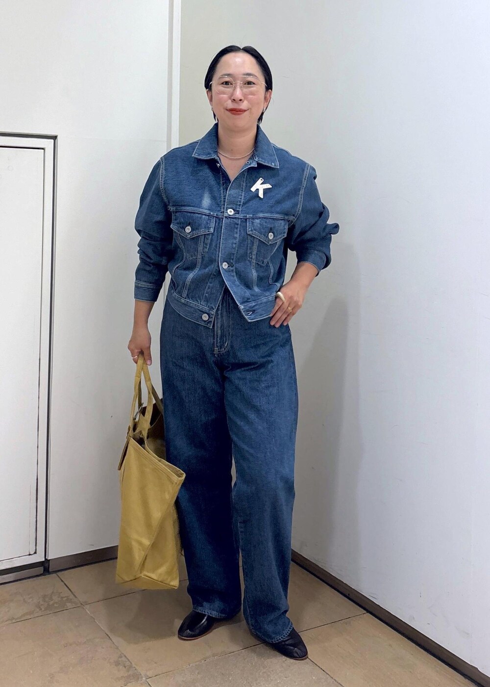 ブルー系のデニムジャケット、ブルー系のデニムパンツ、ブラック系のパンプスを着用したレディースの秋コーディネートの2枚目の写真