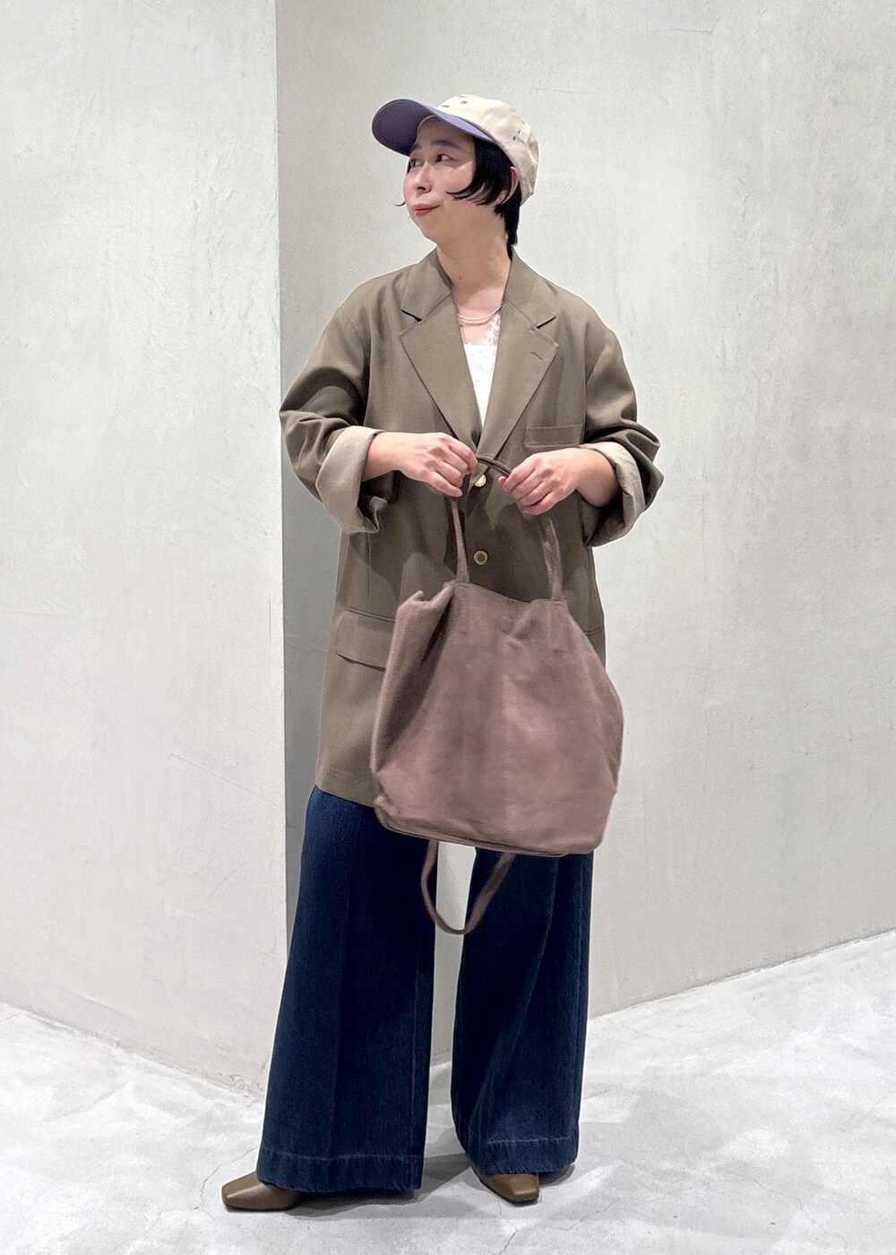 ブラウン系のパンプス、ホワイト系のキャミソール、ブルー系のデニムパンツを着用したレディースの冬コーディネートの4枚目の写真