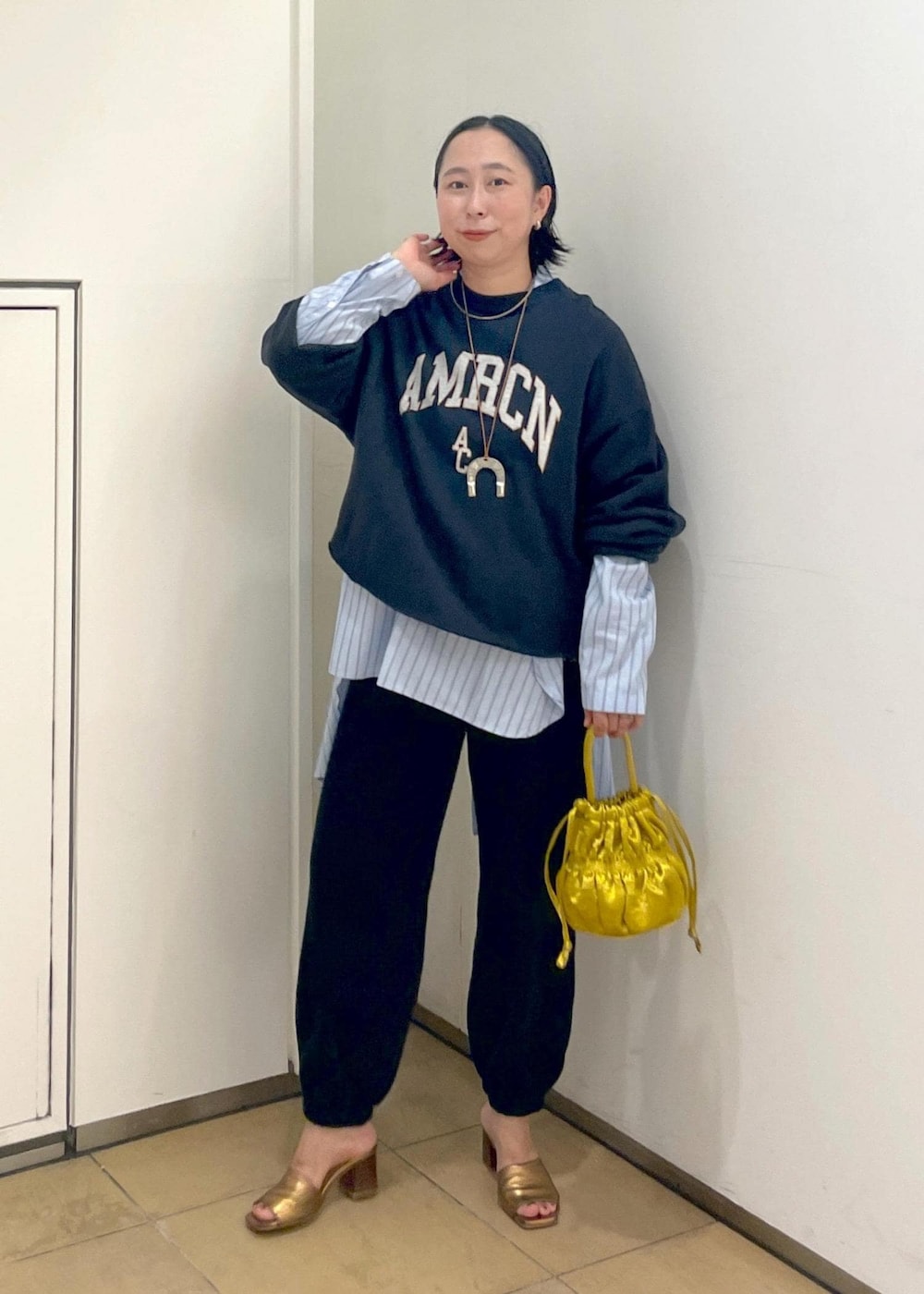 イエロー系のショルダーバッグ、ブラック系のスウェット、ブラック系のスウェットパンツを着用したレディースの夏コーディネートの3枚目の写真