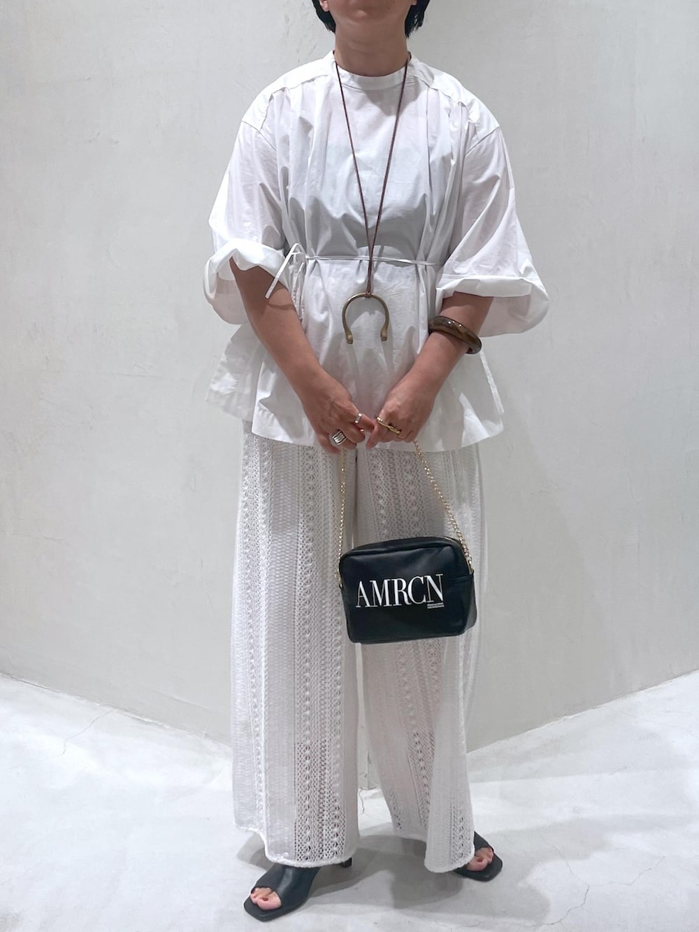 ブラック系のトートバッグ、ホワイト系のその他パンツ、ブラック系のサンダルを着用したレディースの夏コーディネートの5枚目の写真