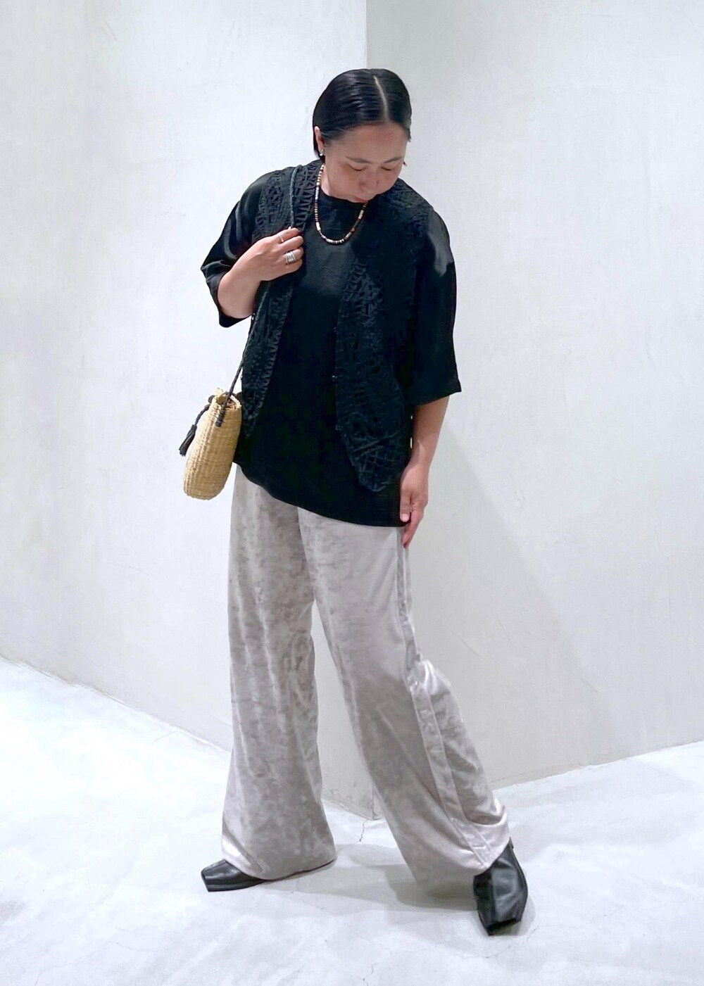 ベージュ系のかごバッグ、ブラック系のベスト、ベージュ系のその他パンツを着用したレディースの夏コーディネートの3枚目の写真