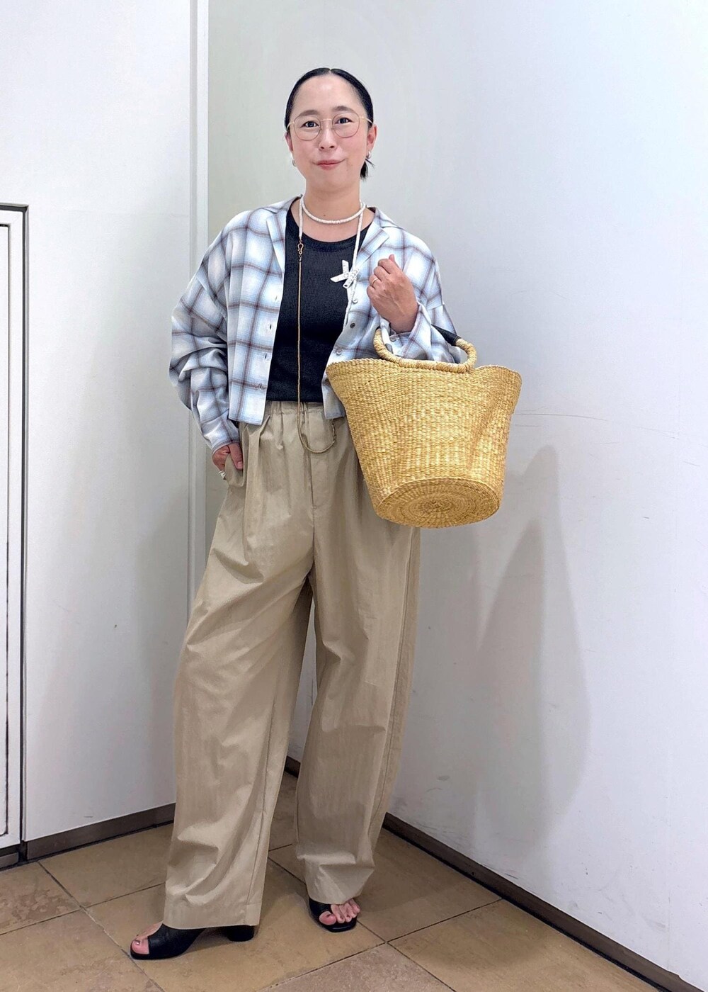 ホワイト系のトートバッグ、ブラック系のサンダル、グレー系のタンクトップを着用したレディースの夏コーディネートの4枚目の写真