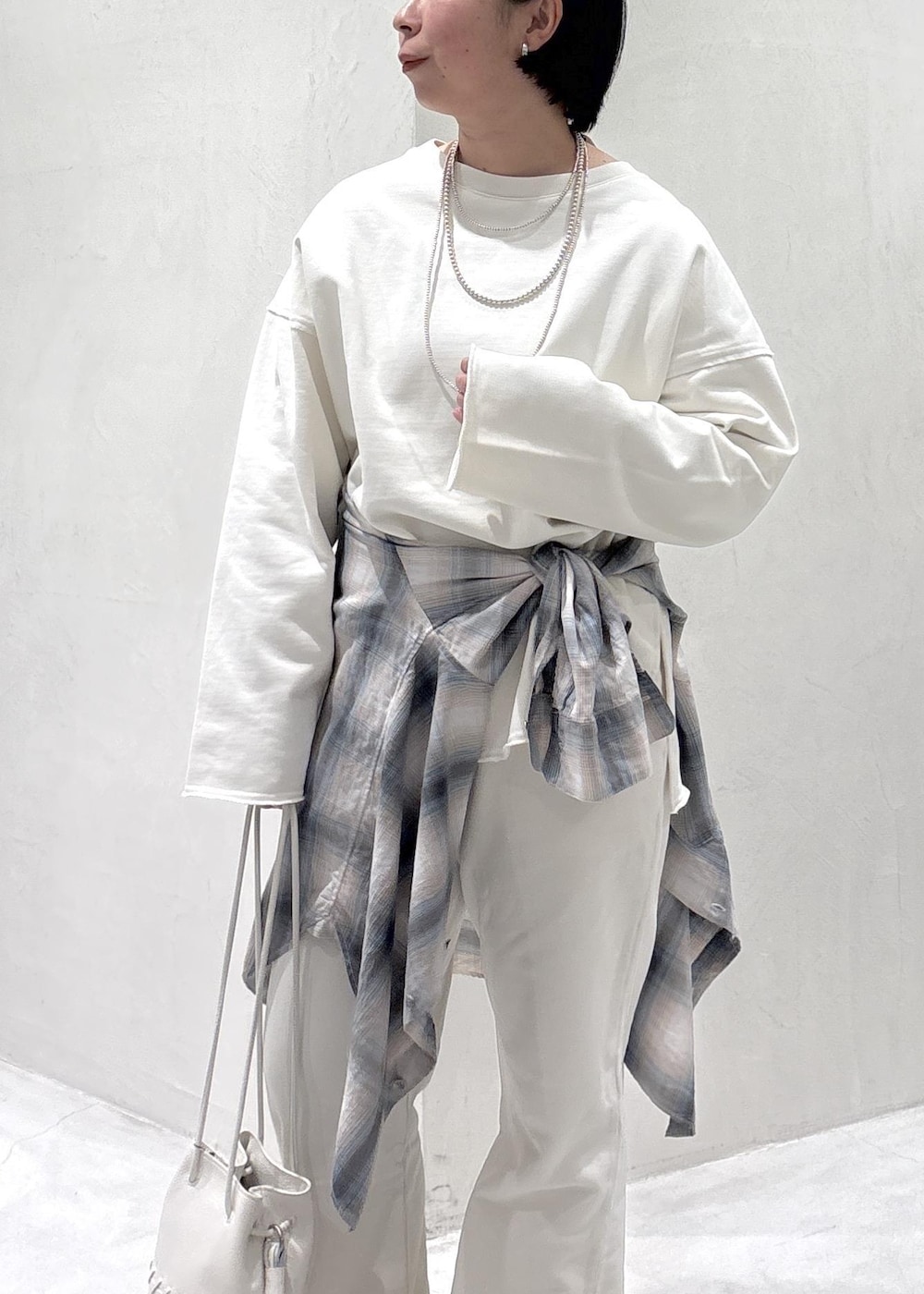 ブラック系のスニーカー、ホワイト系のショルダーバッグ、ブルー系のシャツ/ブラウスを着用したレディースの春コーディネートの5枚目の写真