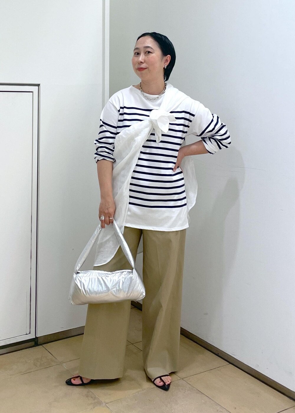 ブラック系のサンダル、シルバー系のハンドバッグ、ホワイト系のシャツ/ブラウスを着用したレディースの春コーディネートの2枚目の写真