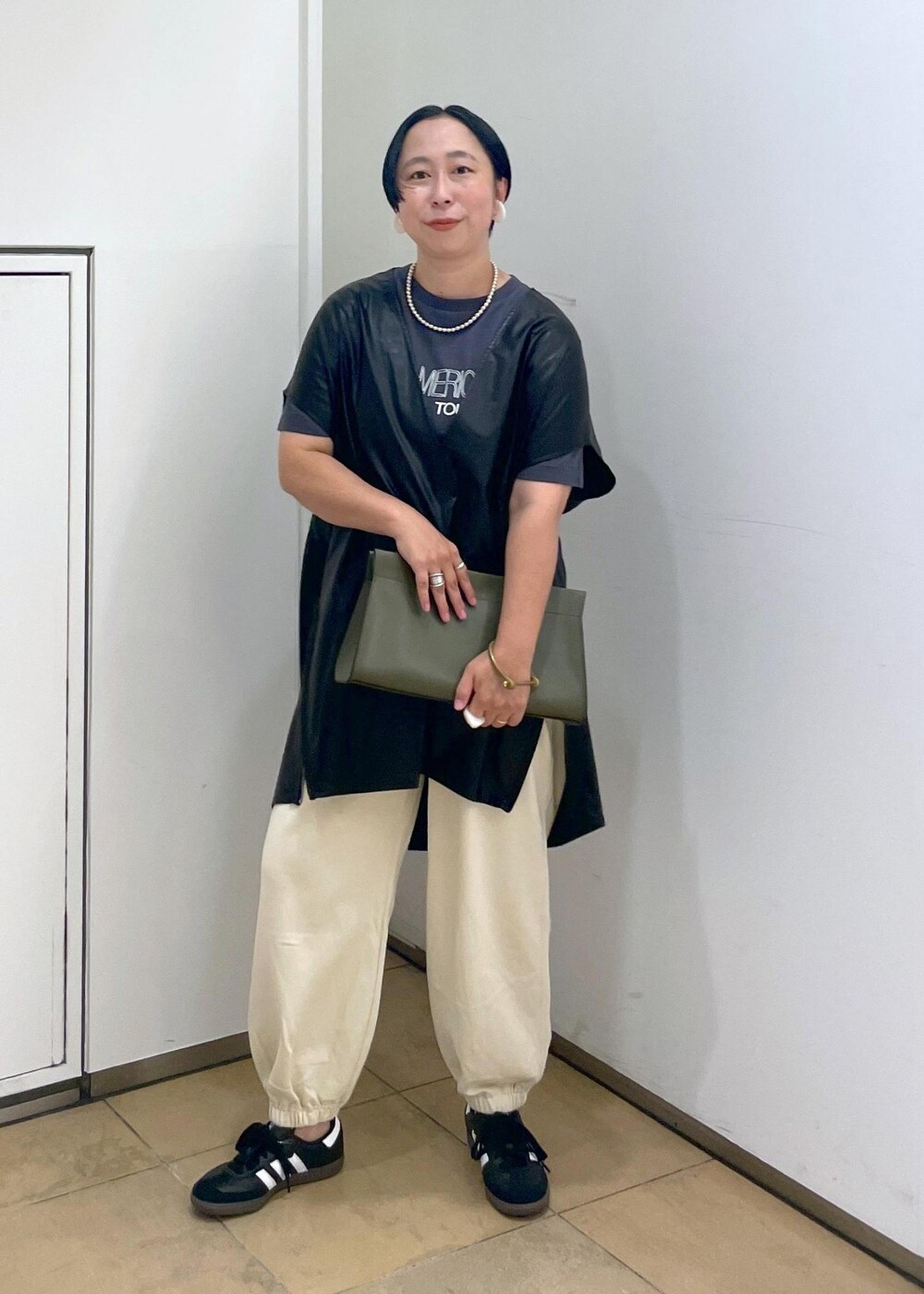 グリーン系のショルダーバッグ、ブラック系のTシャツ/カットソー、ホワイト系のスウェットパンツを着用したレディースの夏コーディネートの3枚目の写真