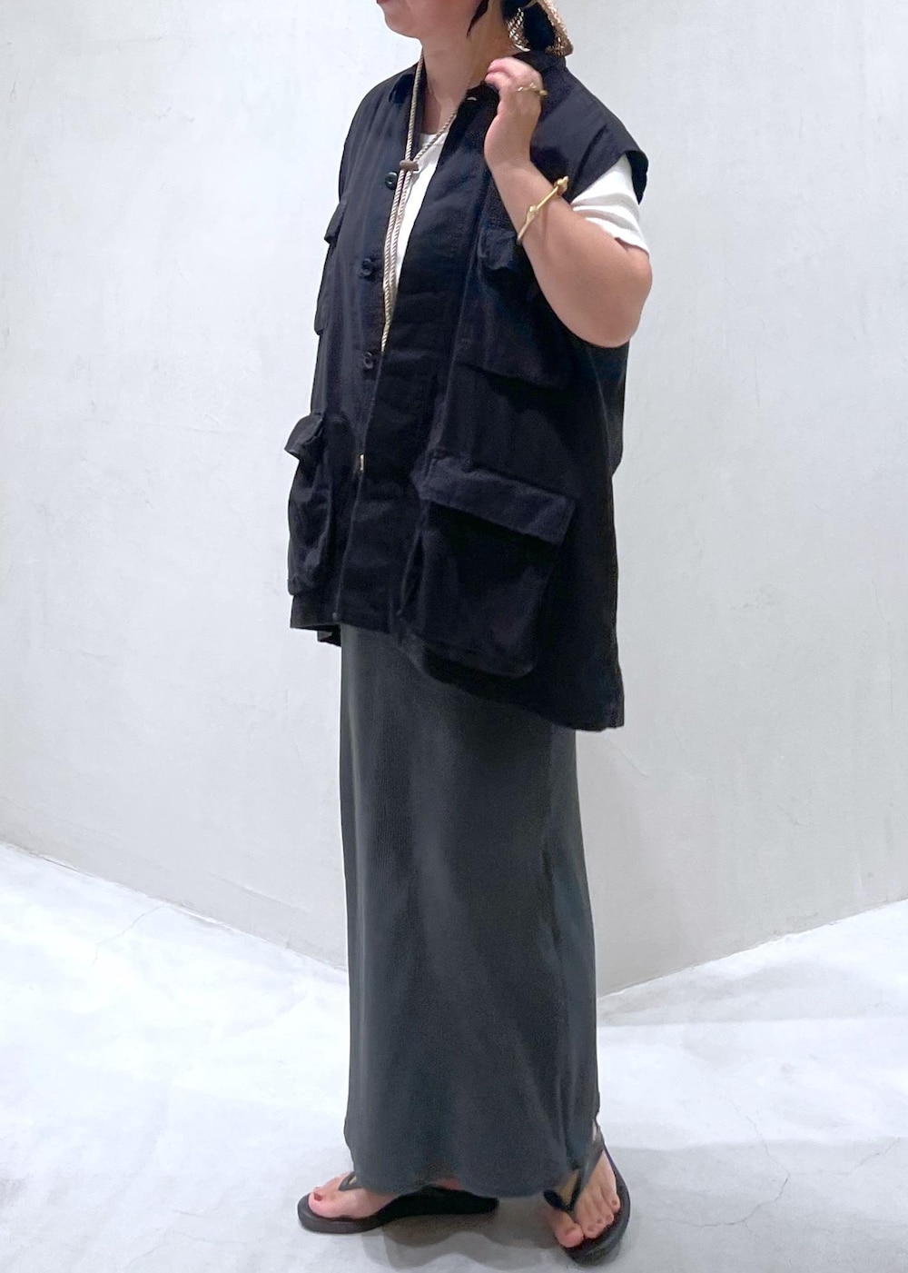 ブラック系のサンダル、ブラック系のベスト、ホワイト系のTシャツ/カットソーを着用したレディースの夏コーディネートの2枚目の写真