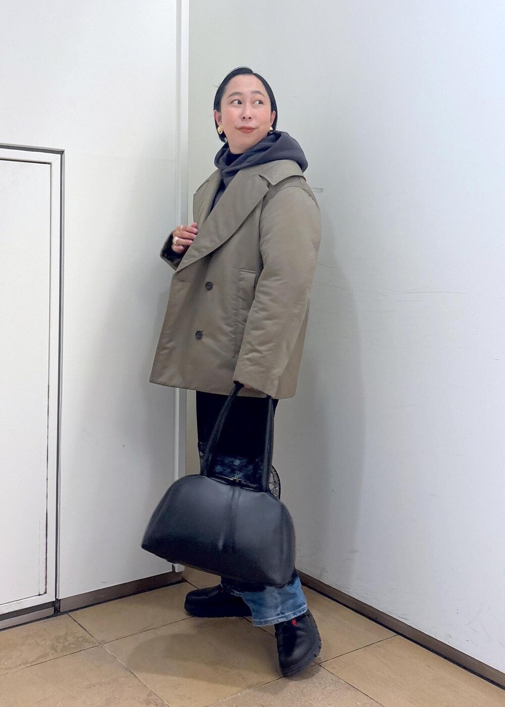 グレー系のパーカー、グリーン系のダウンジャケット/コート、ブラック系のボストンバッグを着用したレディースの冬コーディネートの5枚目の写真