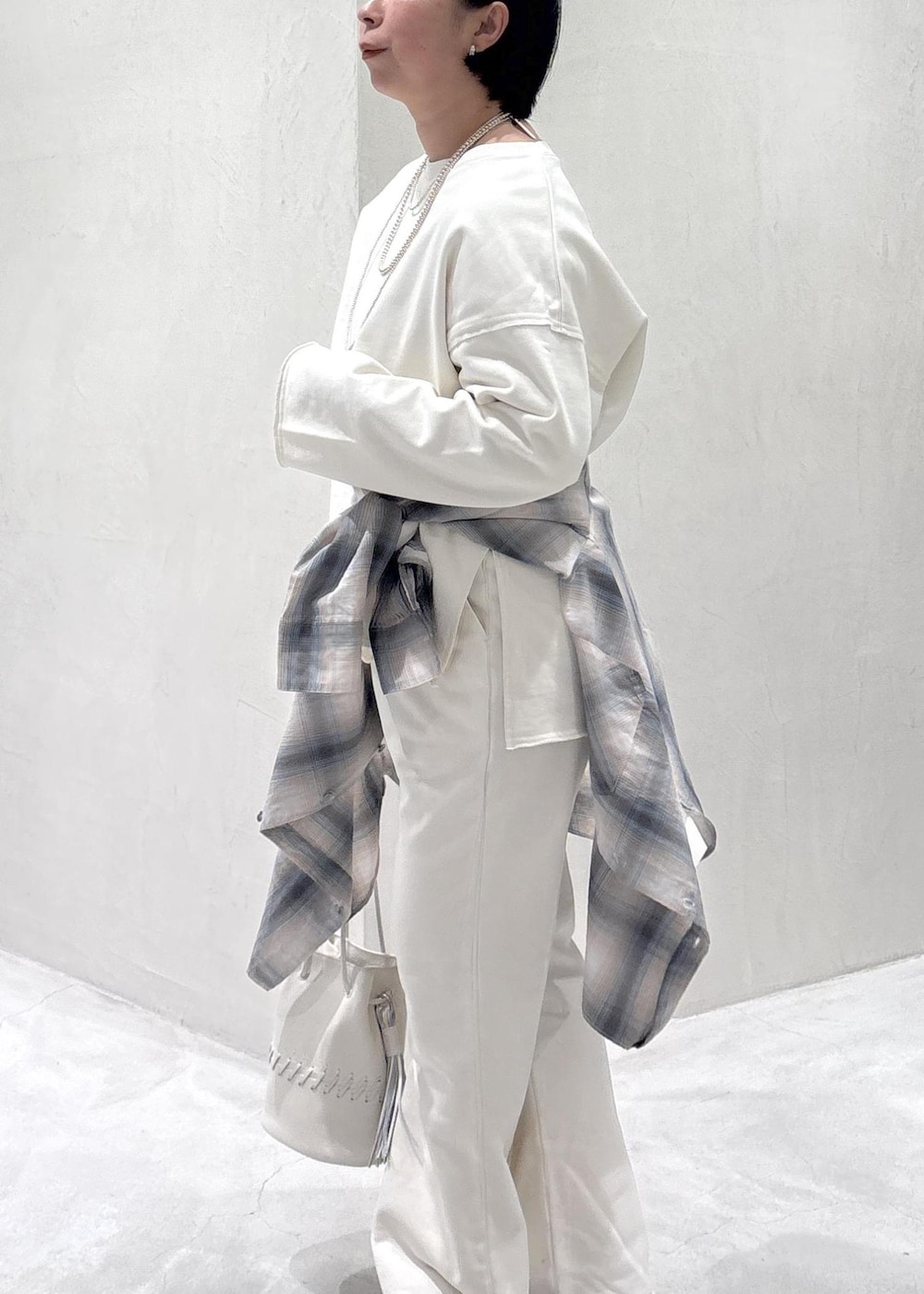 ブラック系のスニーカー、ホワイト系のショルダーバッグ、ブルー系のシャツ/ブラウスを着用したレディースの春コーディネートの6枚目の写真