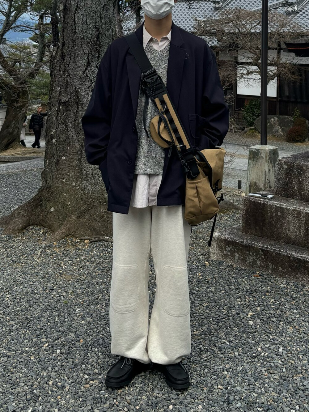 ブラック系のテーラードジャケット、ベージュ系のバッグ、ホワイト系のスウェットパンツを着用したメンズの春コーディネートの4枚目の写真
