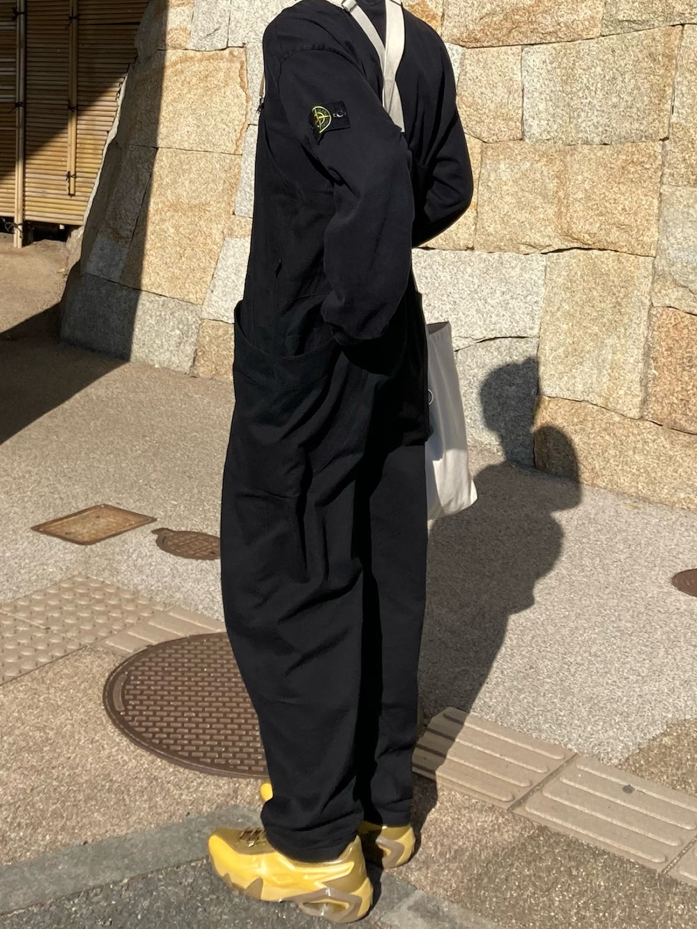 ブラック系のスウェット、ブラック系のサロペット/オーバーオール、イエロー系のスニーカーを着用したメンズの冬コーディネートの2枚目の写真