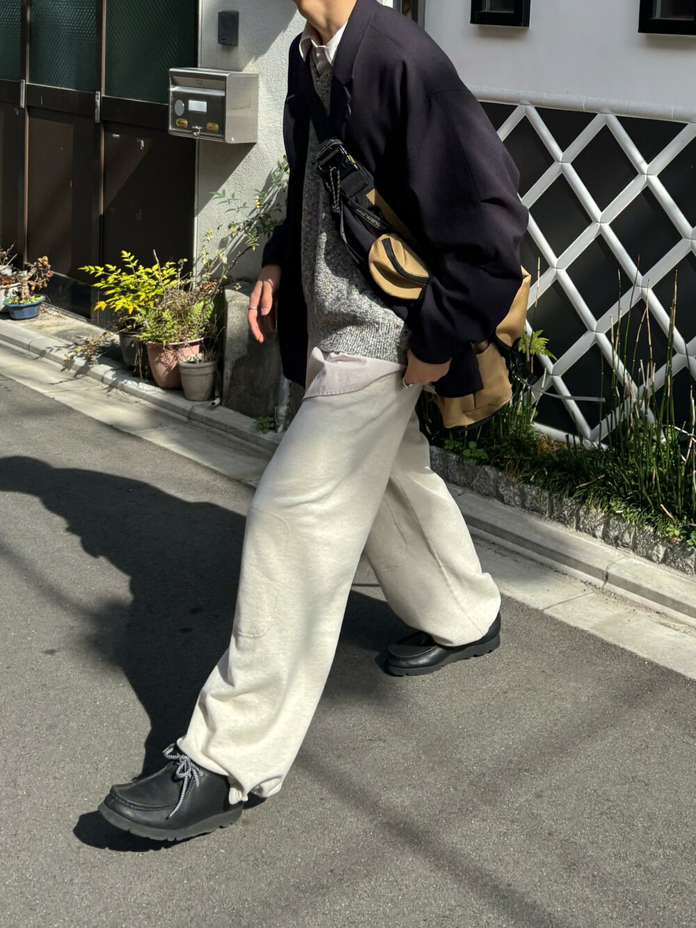 ブラック系のテーラードジャケット、ベージュ系のバッグ、ホワイト系のスウェットパンツを着用したメンズの春コーディネートの3枚目の写真