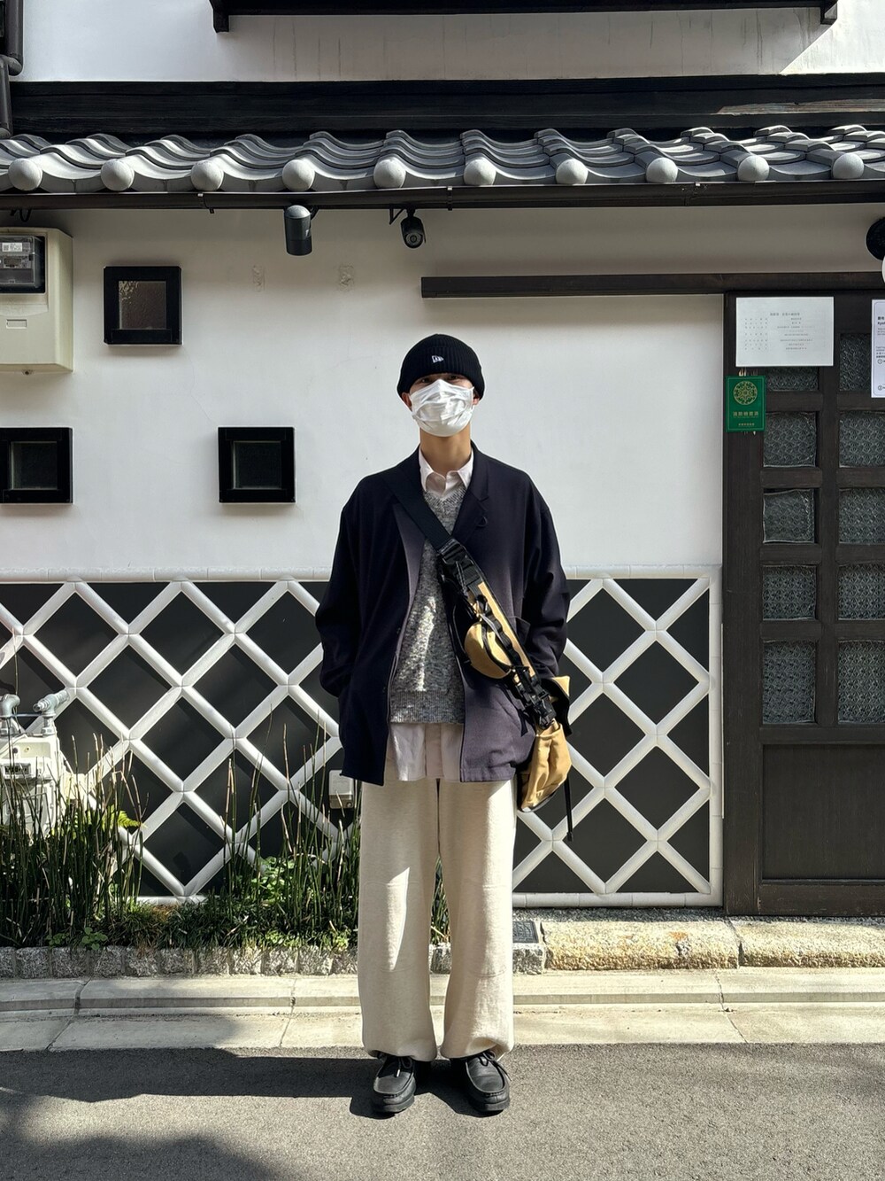 ブラック系のテーラードジャケット、ベージュ系のバッグ、ホワイト系のスウェットパンツを着用したメンズの春コーディネートの2枚目の写真