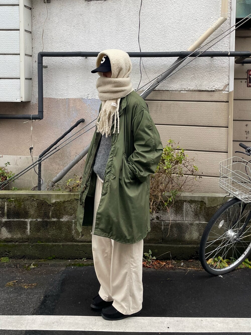 ベージュ系のトップス、グリーン系のミリタリージャケットを着用したメンズの冬コーディネートの2枚目の写真