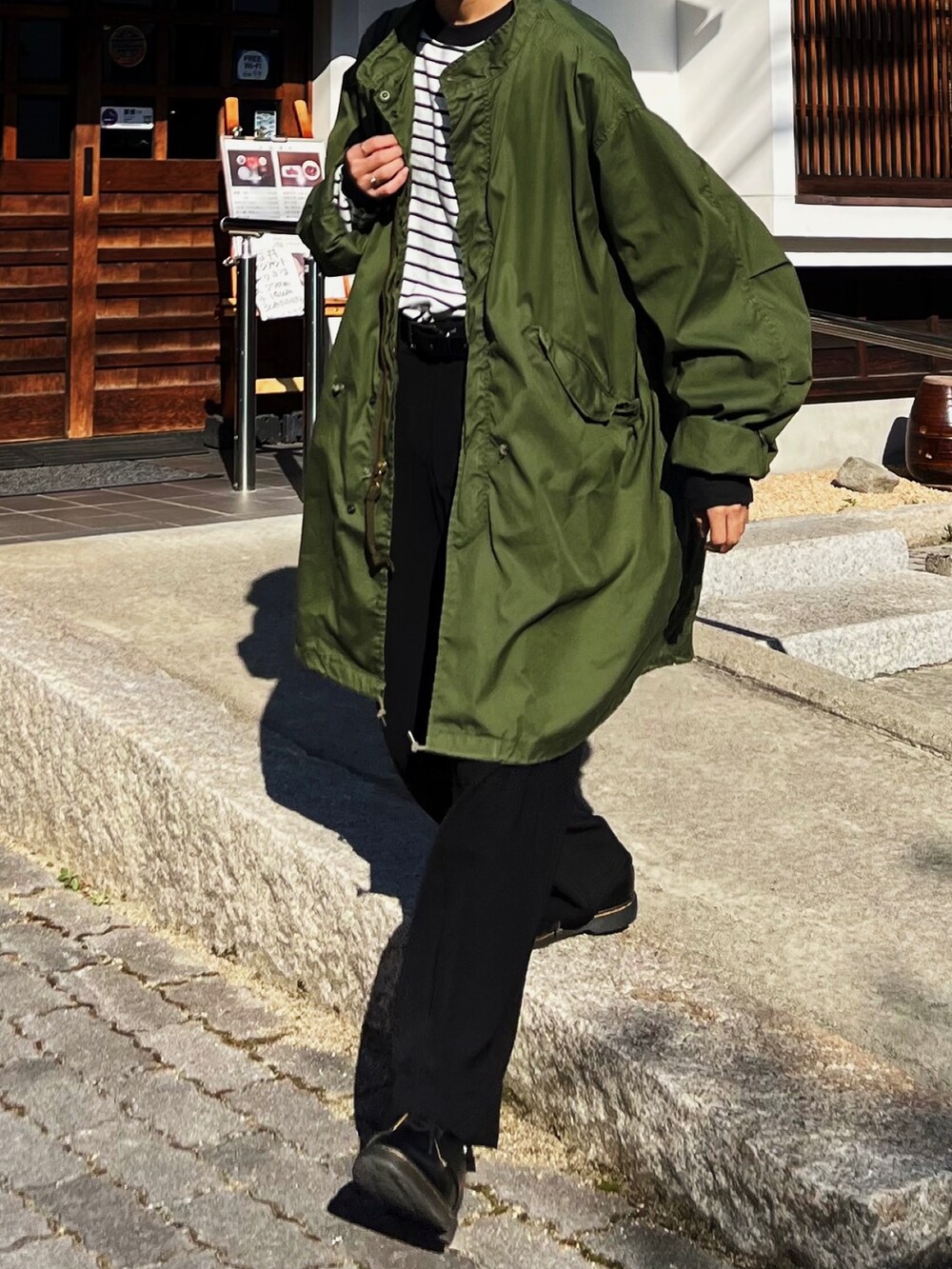 グリーン系のモッズコート、ブラック系のショルダーバッグ、ホワイト系のTシャツ/カットソーを着用したメンズの秋コーディネートの2枚目の写真
