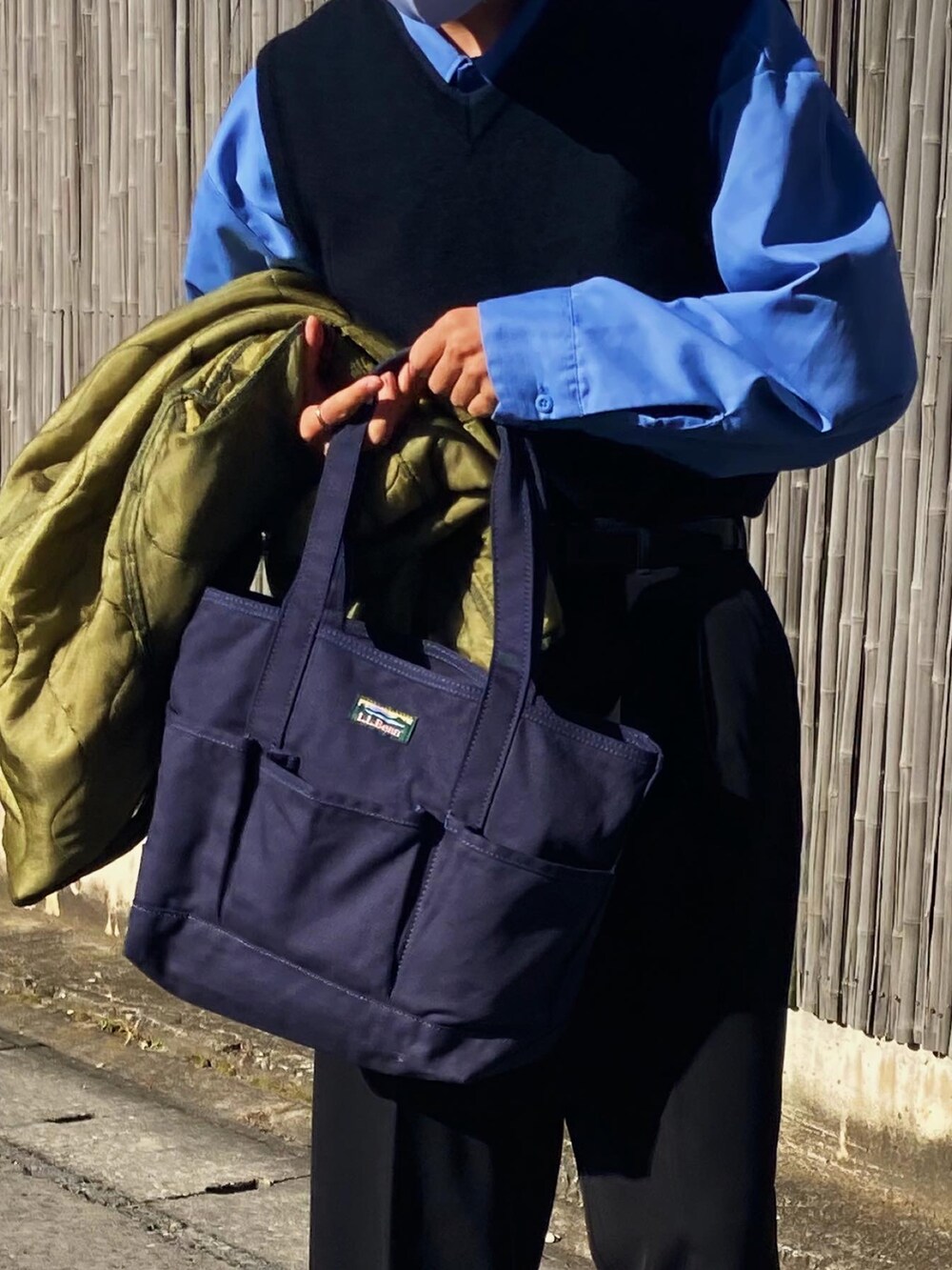 ブラック系のスラックス、グレー系のスニーカー、ブルー系のトートバッグを着用したメンズの秋コーディネートの4枚目の写真