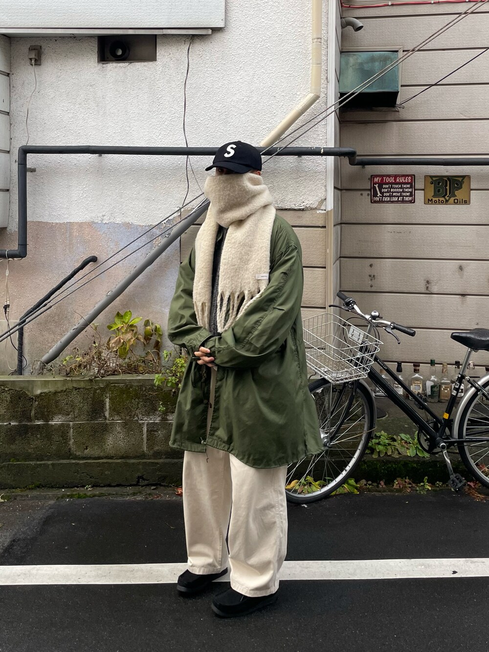 ベージュ系のトップス、グリーン系のミリタリージャケットを着用したメンズの冬コーディネートの4枚目の写真