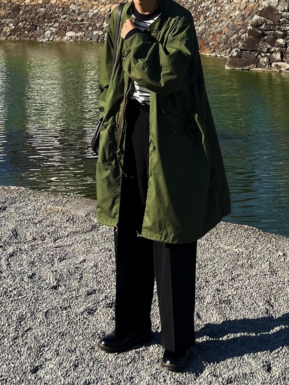 グリーン系のモッズコート、ブラック系のショルダーバッグ、ホワイト系のTシャツ/カットソーを着用したメンズの秋コーディネートの3枚目の写真