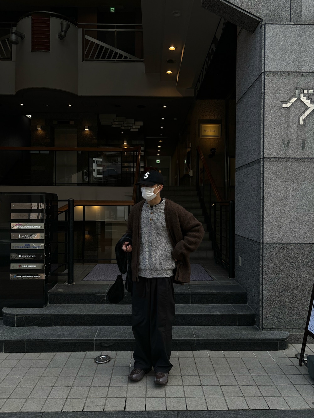 ブラウン系のカーディガン/ボレロ、ブラック系のカーゴパンツ、イエロー系のスニーカーを着用したメンズの春コーディネートの3枚目の写真