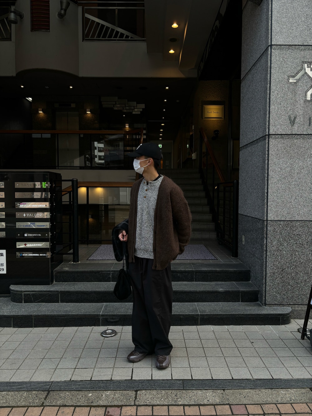 ブラウン系のカーディガン/ボレロ、ブラック系のカーゴパンツ、イエロー系のスニーカーを着用したメンズの春コーディネートの2枚目の写真